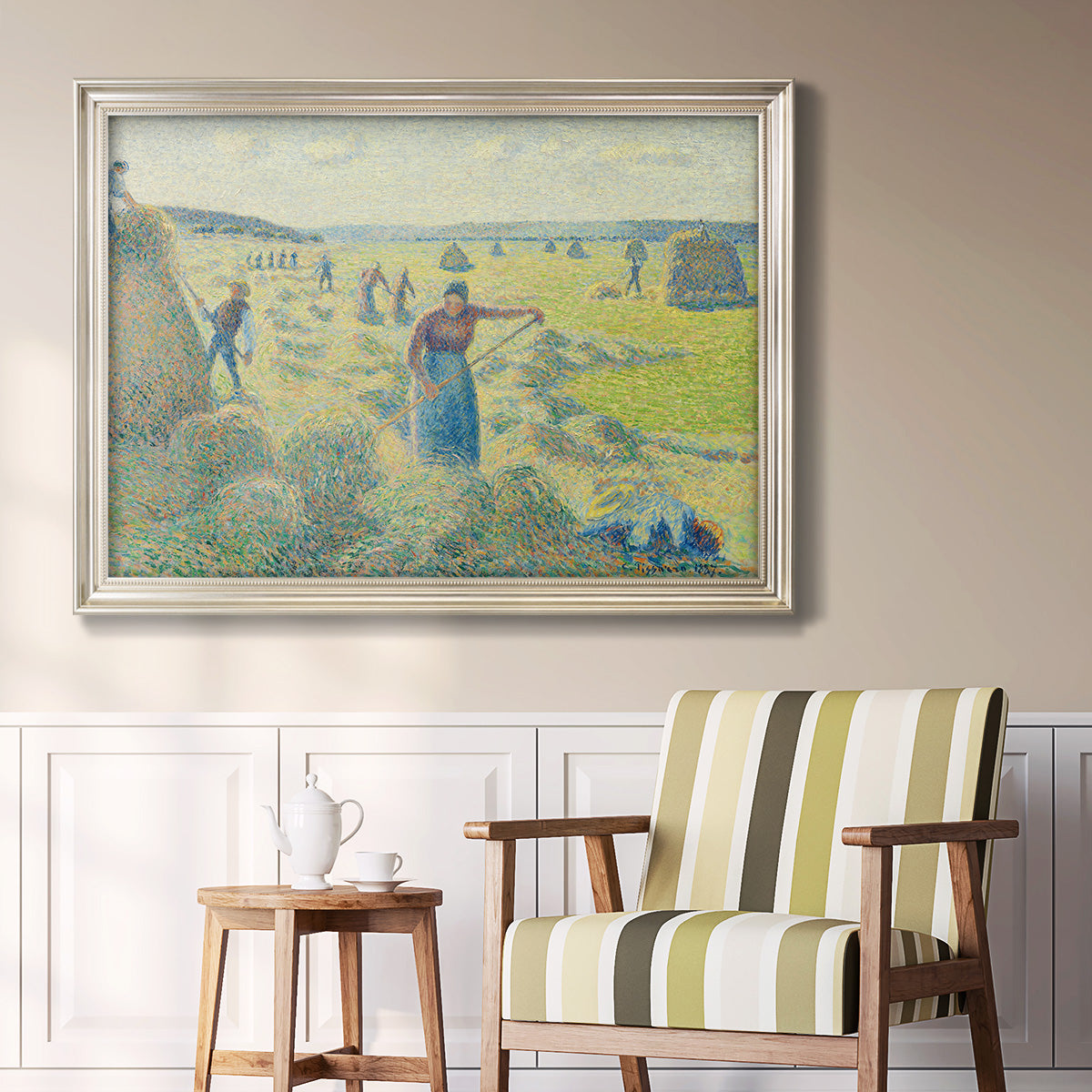 Impressionist rural hay harvest landscape by Camille Pissarro in an ornate champagne frame displayed in a light-toned interior setting.