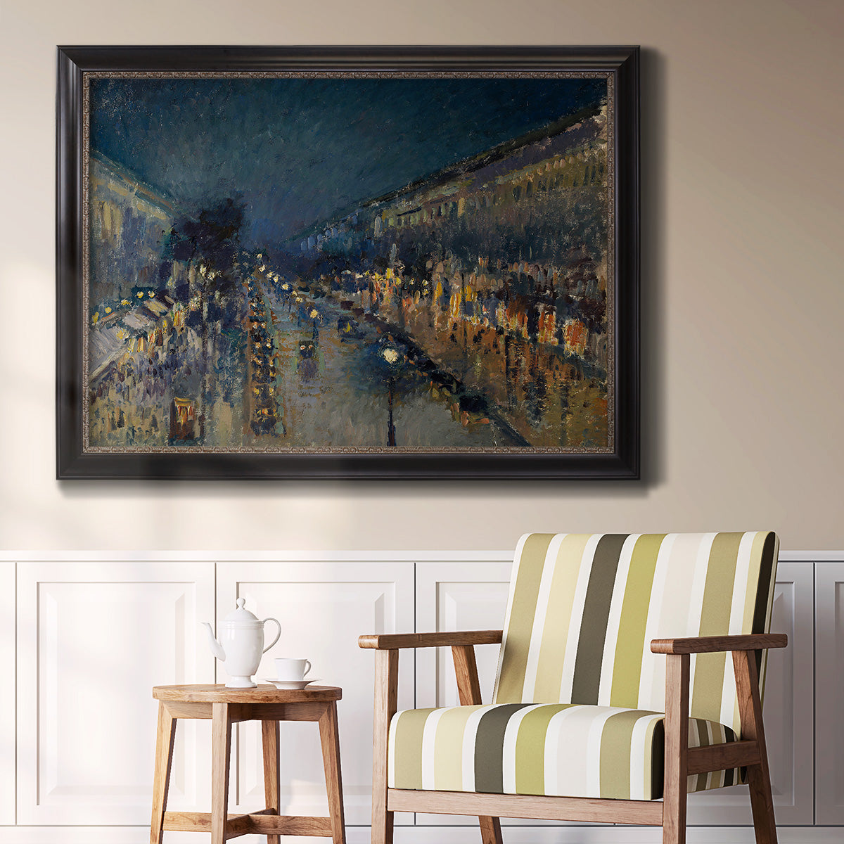 Impressionist nighttime Paris street scene by Camille Pissarro in an ornate black frame with gilded inner detail displayed in a light-toned interior setting.