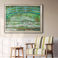 Impressionist garden scene with Japanese bridge and water lilies by Claude Monet in an ornate champagne frame displayed in a light-toned interior setting.
