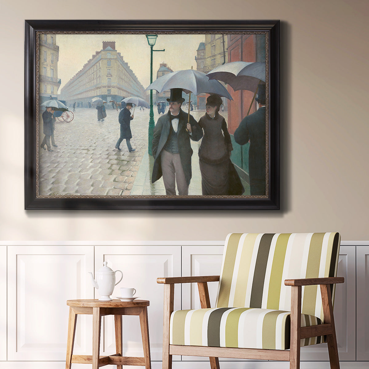 Impressionist urban street scene in the rain by Gustave Caillebotte in an ornate black frame with gilded inner detail displayed in a light-toned interior setting.