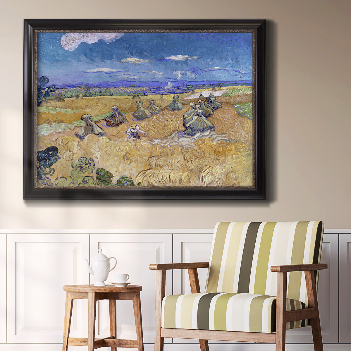 Impressionist wheat harvest scene by Vincent van Gogh in an ornate black frame with gilded inner detail displayed in a light-toned interior setting.