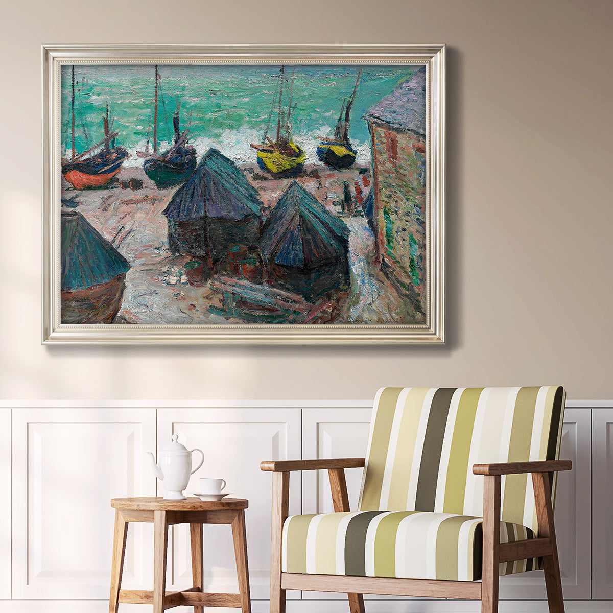 Impressionist coastal beach scene with boats by Claude Monet in an ornate champagne frame displayed in a light-toned interior setting.