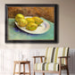 Impressionist still life with lemons by Vincent van Gogh in an ornate black frame with gilded inner detail displayed in a light-toned interior setting.