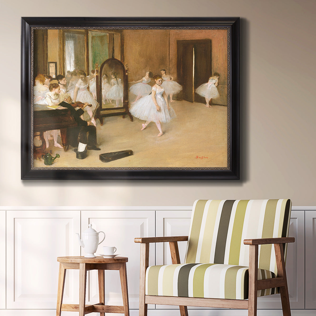 Impressionist dance class interior scene by Edgar Degas in an ornate black frame with gilded inner detail displayed in a light-toned interior setting.