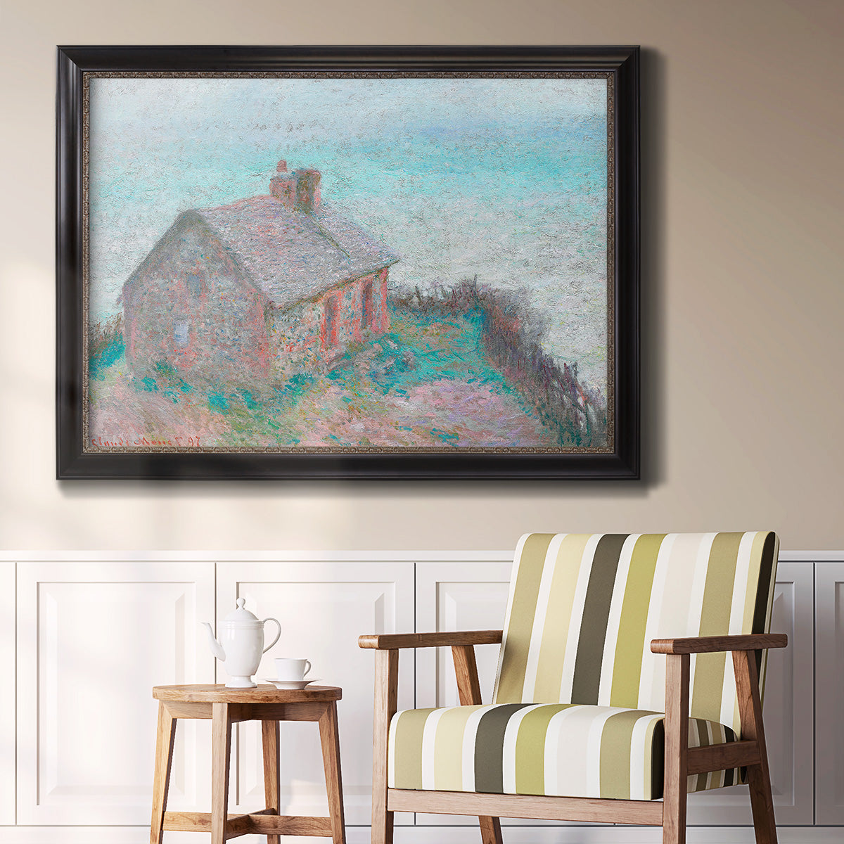 Impressionist coastal building landscape by Claude Monet in an ornate black frame with gilded inner detail displayed in a light-toned interior setting.