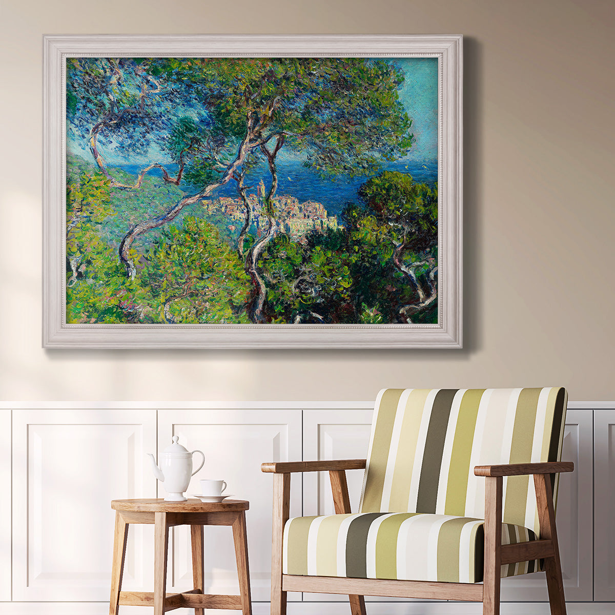 Impressionist Mediterranean coastal landscape by Claude Monet in an ornate weathered white frame displayed in a light-toned interior setting.