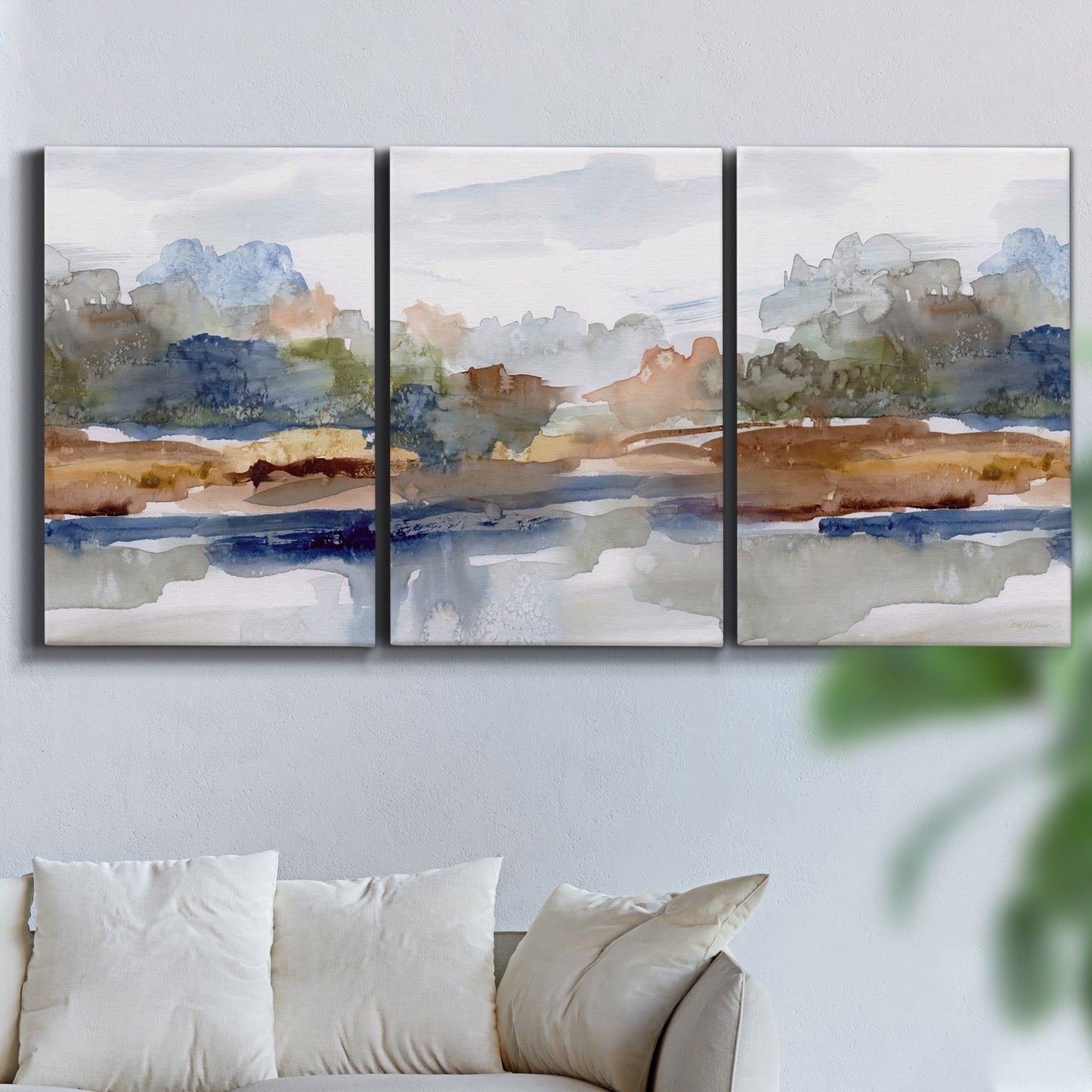 Three-panel canvas wall art featuring layered abstract mountain forms, displayed in a living room above a sofa.