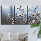 Three-panel canvas wall art featuring delicate spring blossoms on branches, displayed in a living room above a sofa.
