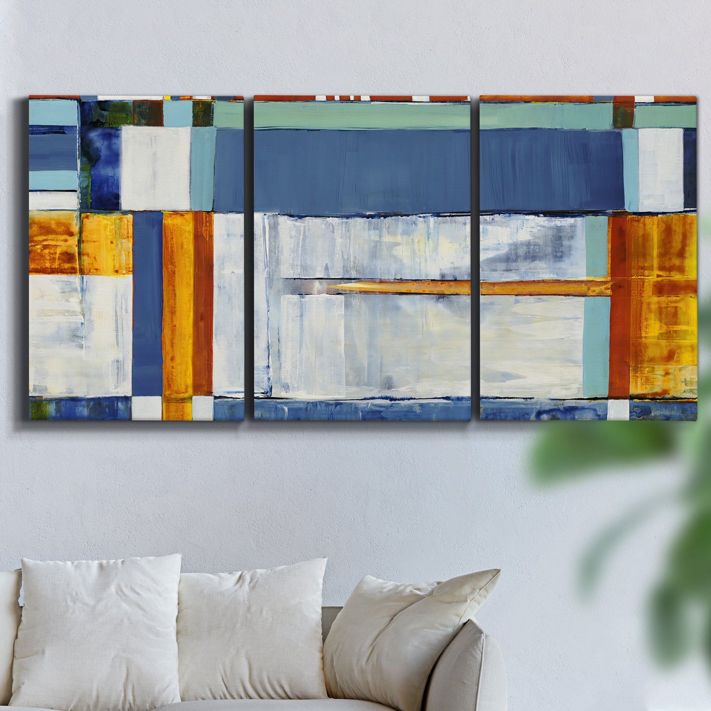Three-panel canvas wall art featuring bright mid century geometric abstraction, displayed in a living room above a sofa.
