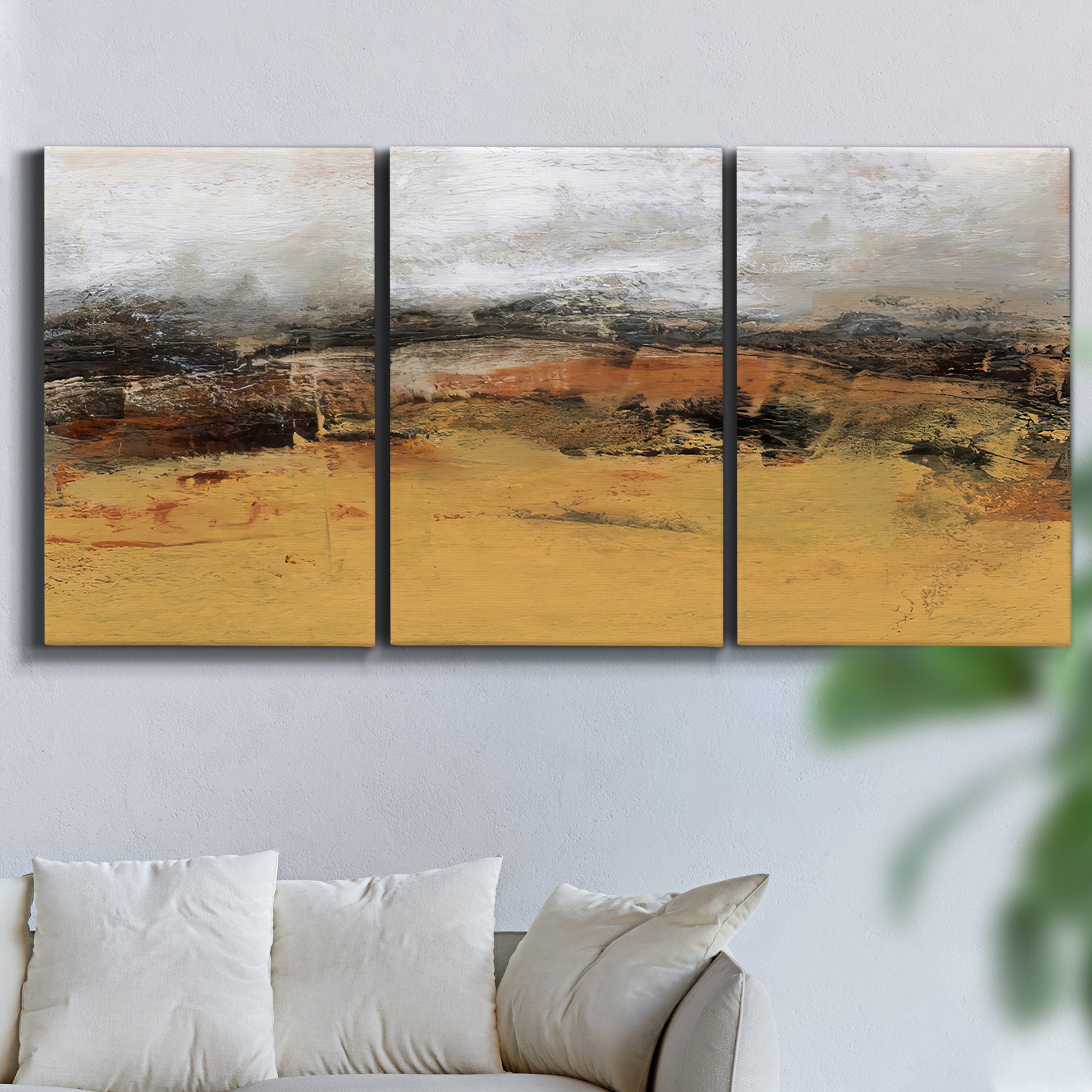 Three-panel canvas wall art featuring abstract bridge landscape in ochre, displayed in a living room above a sofa.