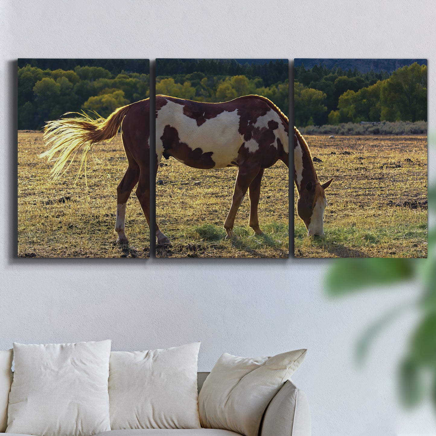 Three-panel canvas wall art featuring horses standing near farmhouse, displayed in a living room above a sofa.