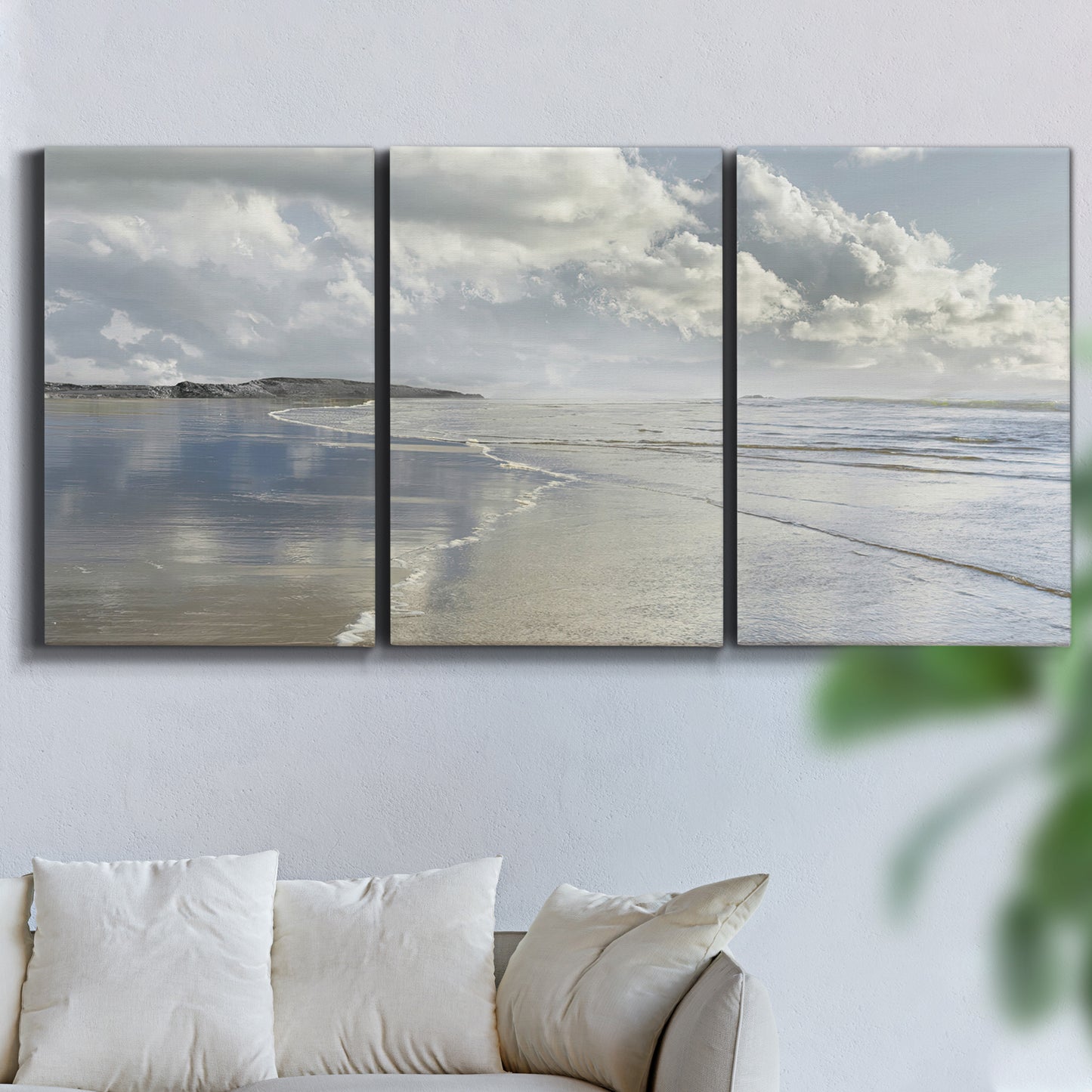Three-panel canvas wall art featuring endless beach meeting ocean horizon, displayed in a living room above a sofa.
