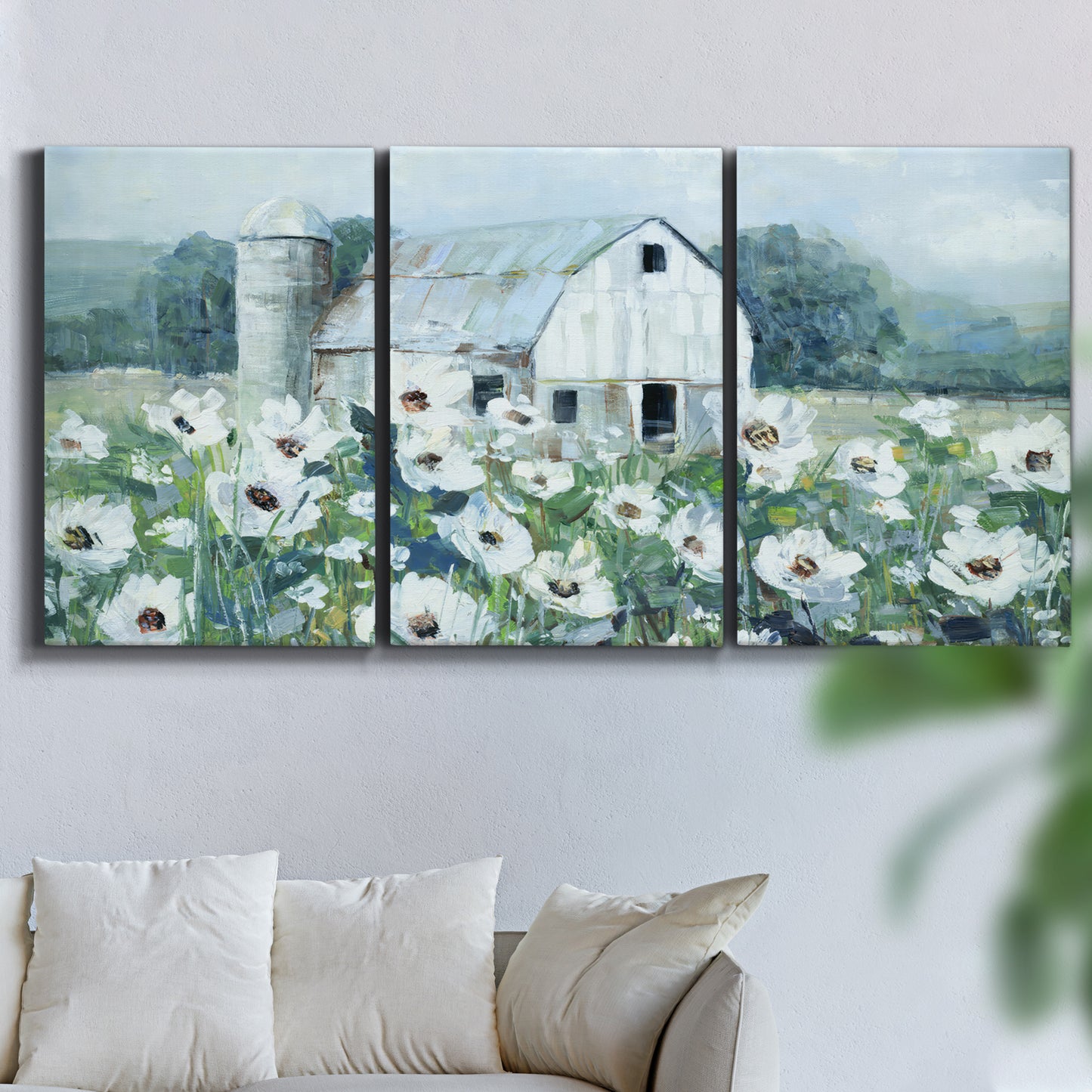 Three-panel canvas wall art featuring pastoral farmland with open fields, displayed in a living room above a sofa.