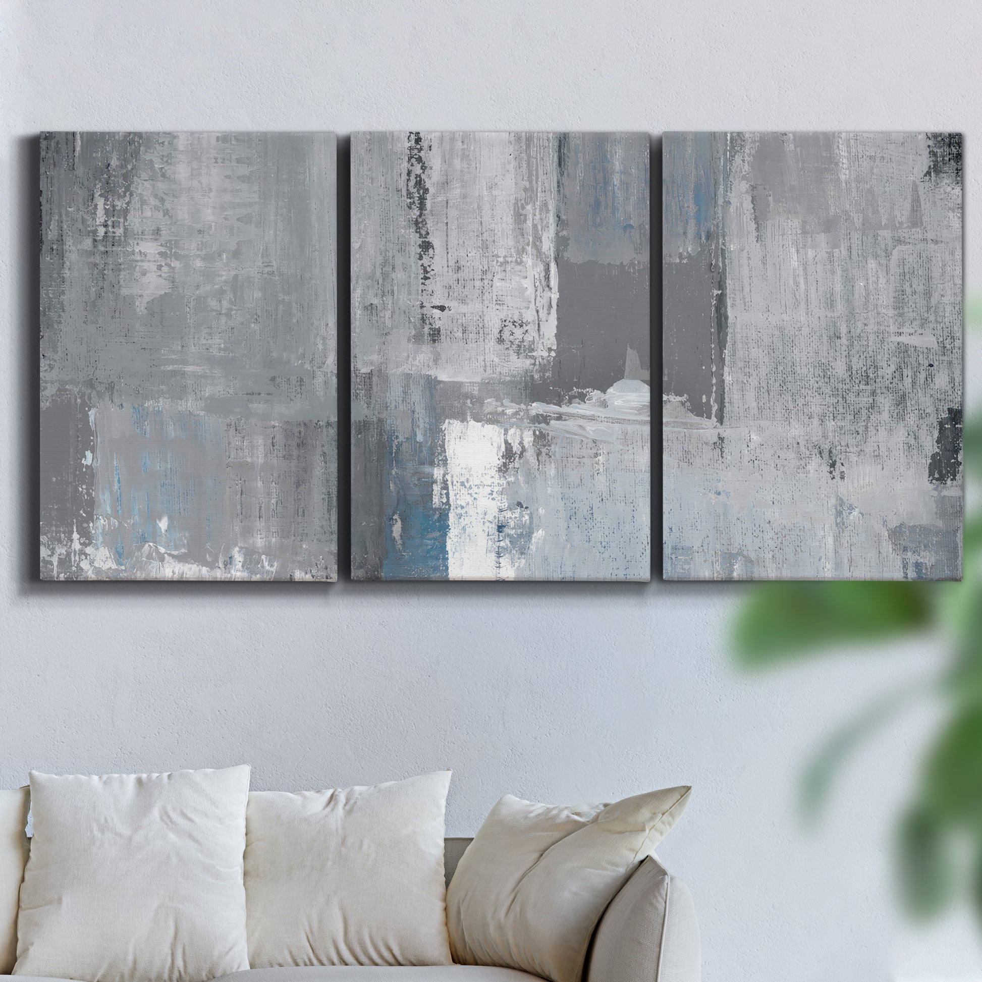 Three-panel canvas wall art featuring cool toned industrial abstract blues, displayed in a living room above a sofa.