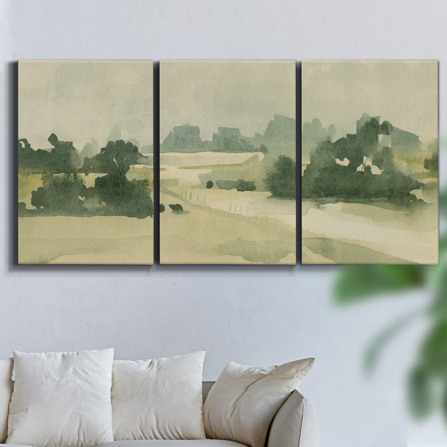 Three-panel canvas wall art featuring pasture landscape in soft watercolor, displayed in a living room above a sofa.