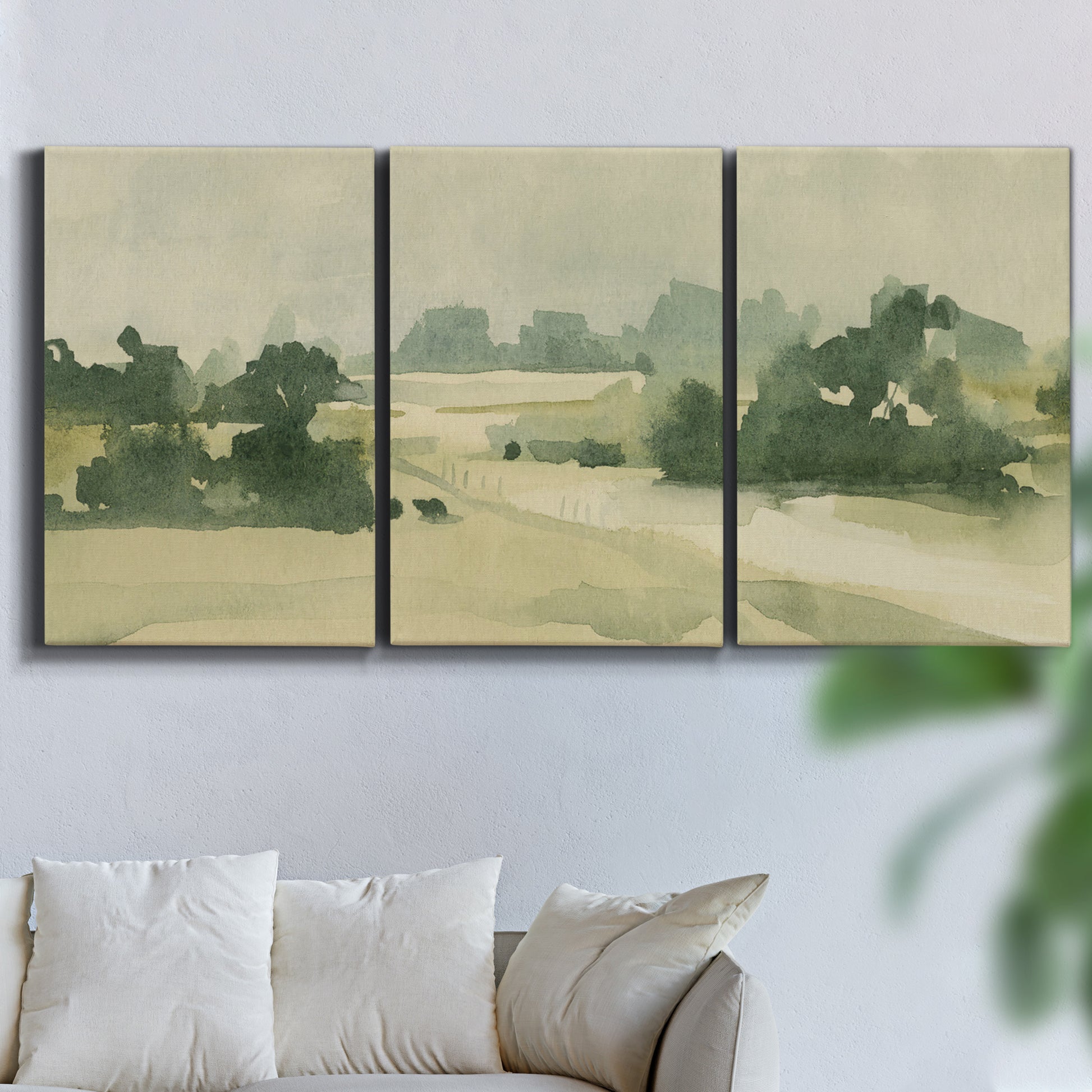 Three-panel canvas wall art featuring pasture landscape in soft watercolor, displayed in a living room above a sofa.