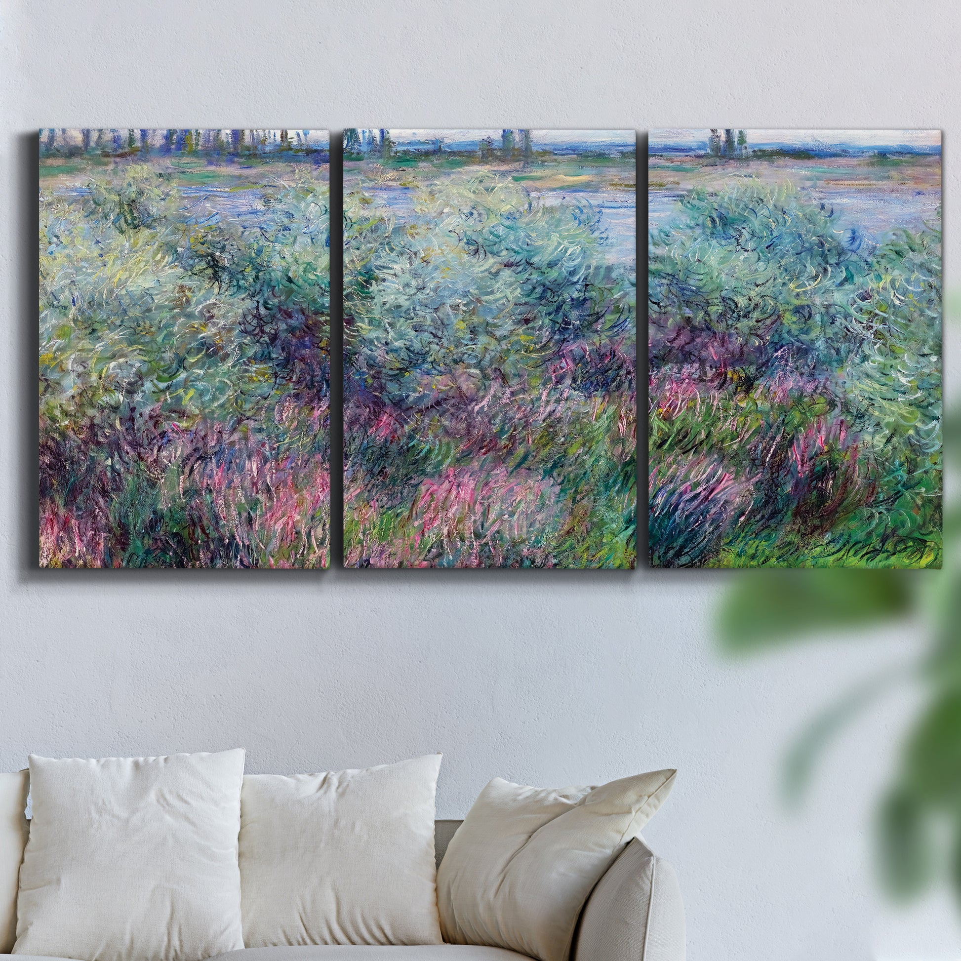 Three-panel canvas wall art featuring flowered riverbank with trees, displayed in a living room above a sofa.