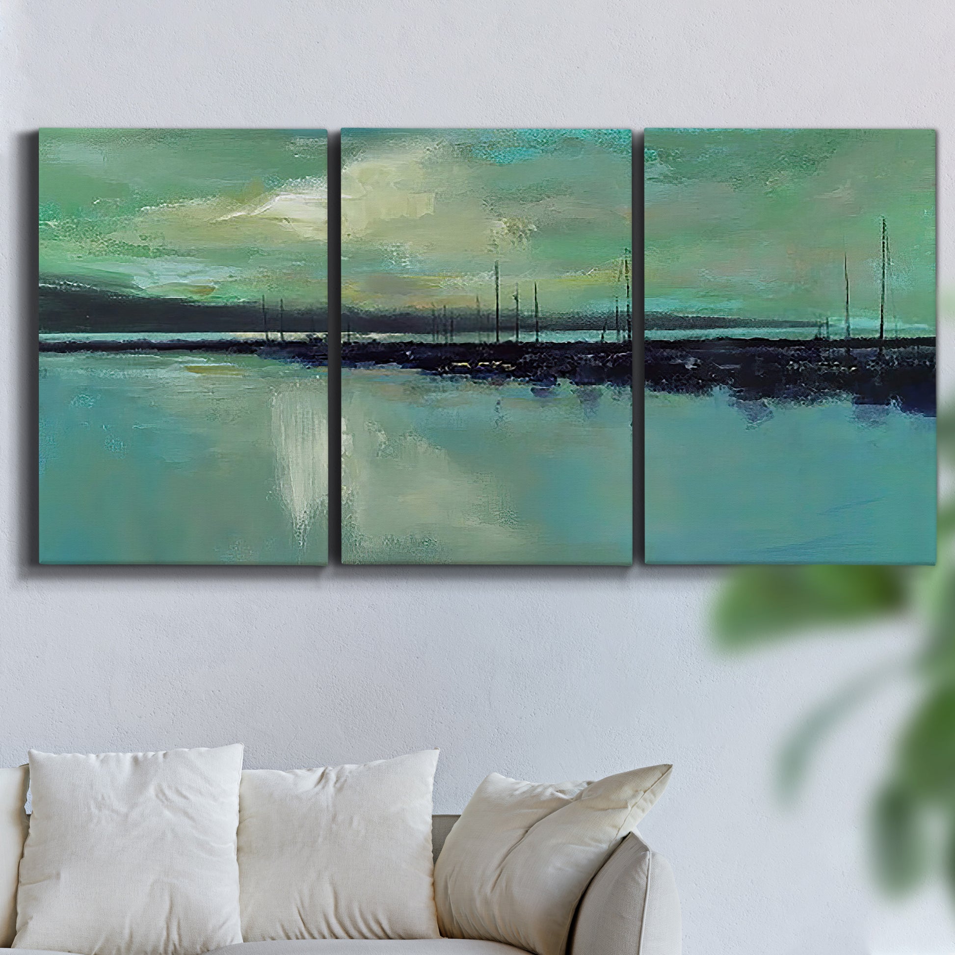 Three-panel canvas wall art featuring calm harbor water with glowing horizon, displayed in a living room above a sofa.