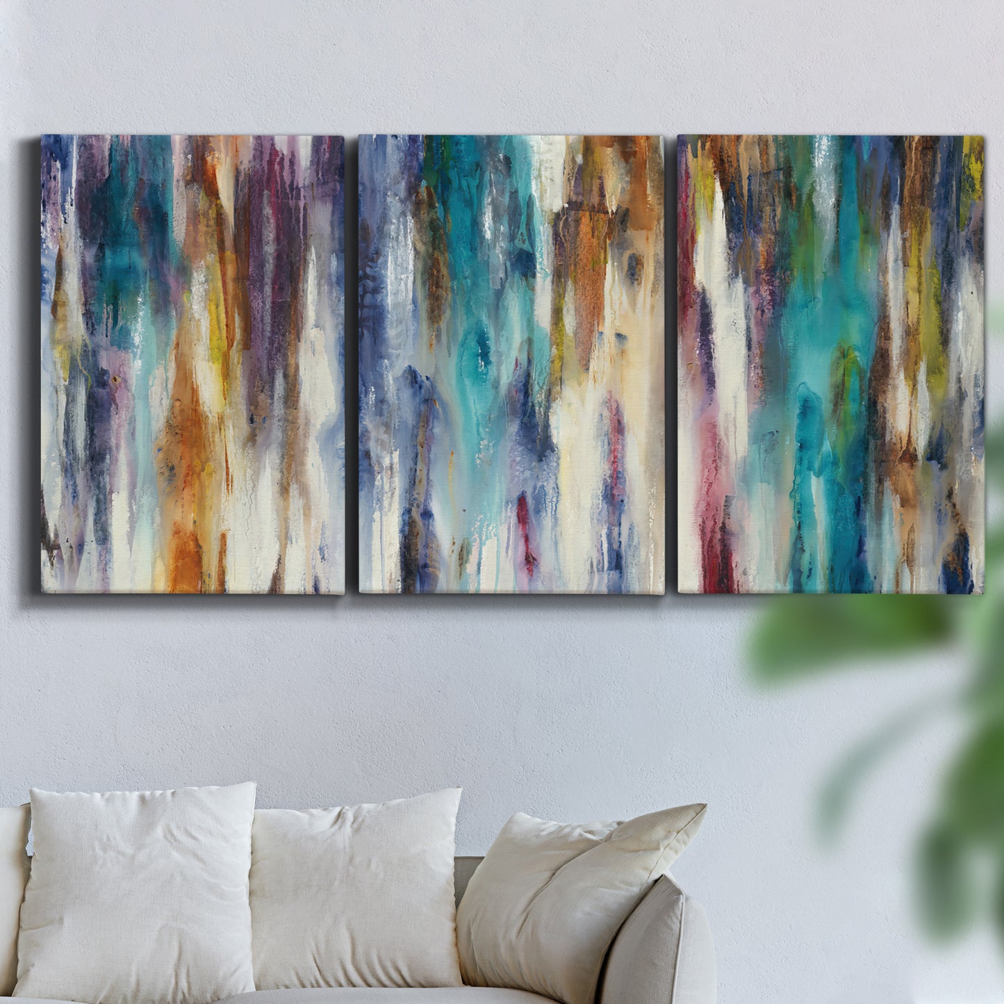 Three-panel canvas wall art featuring abstract shifting color forms, displayed in a living room above a sofa.