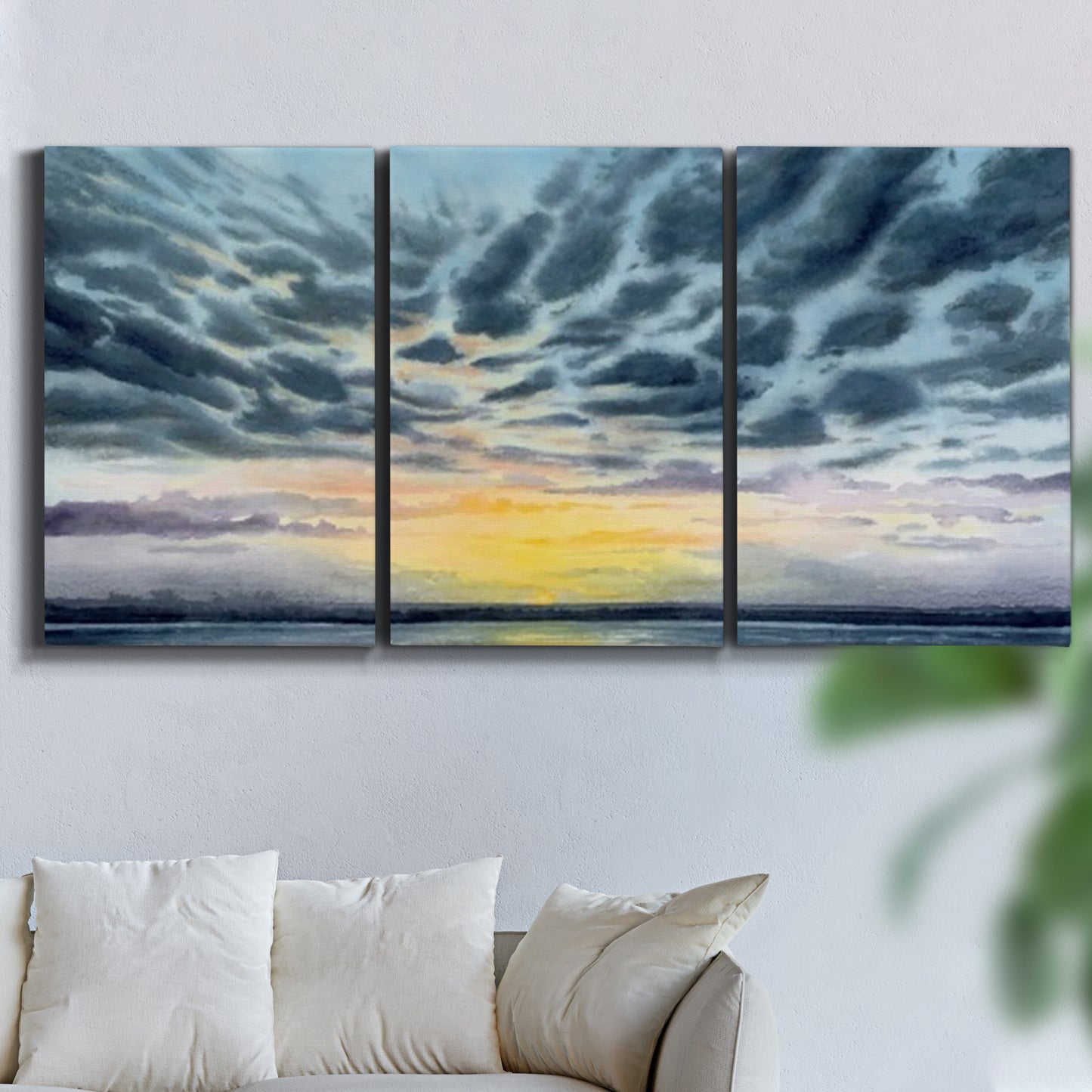 Three-panel canvas wall art featuring tropical coastal sunset over water, displayed in a living room above a sofa.