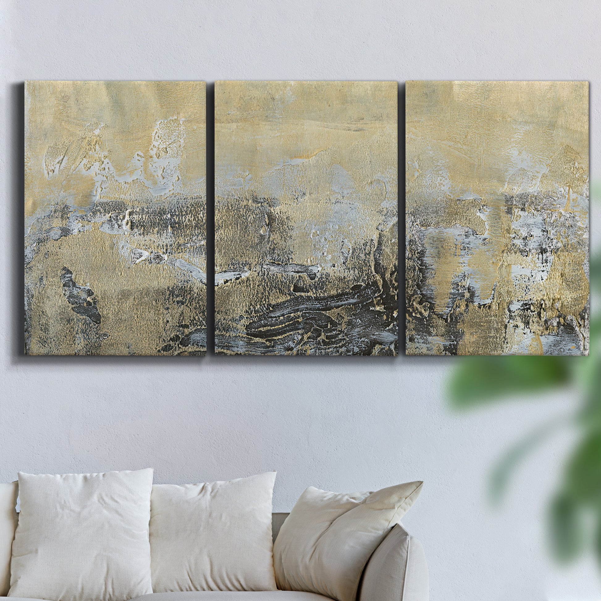 Three-panel canvas wall art featuring gold toned abstract horizon, displayed in a living room above a sofa.