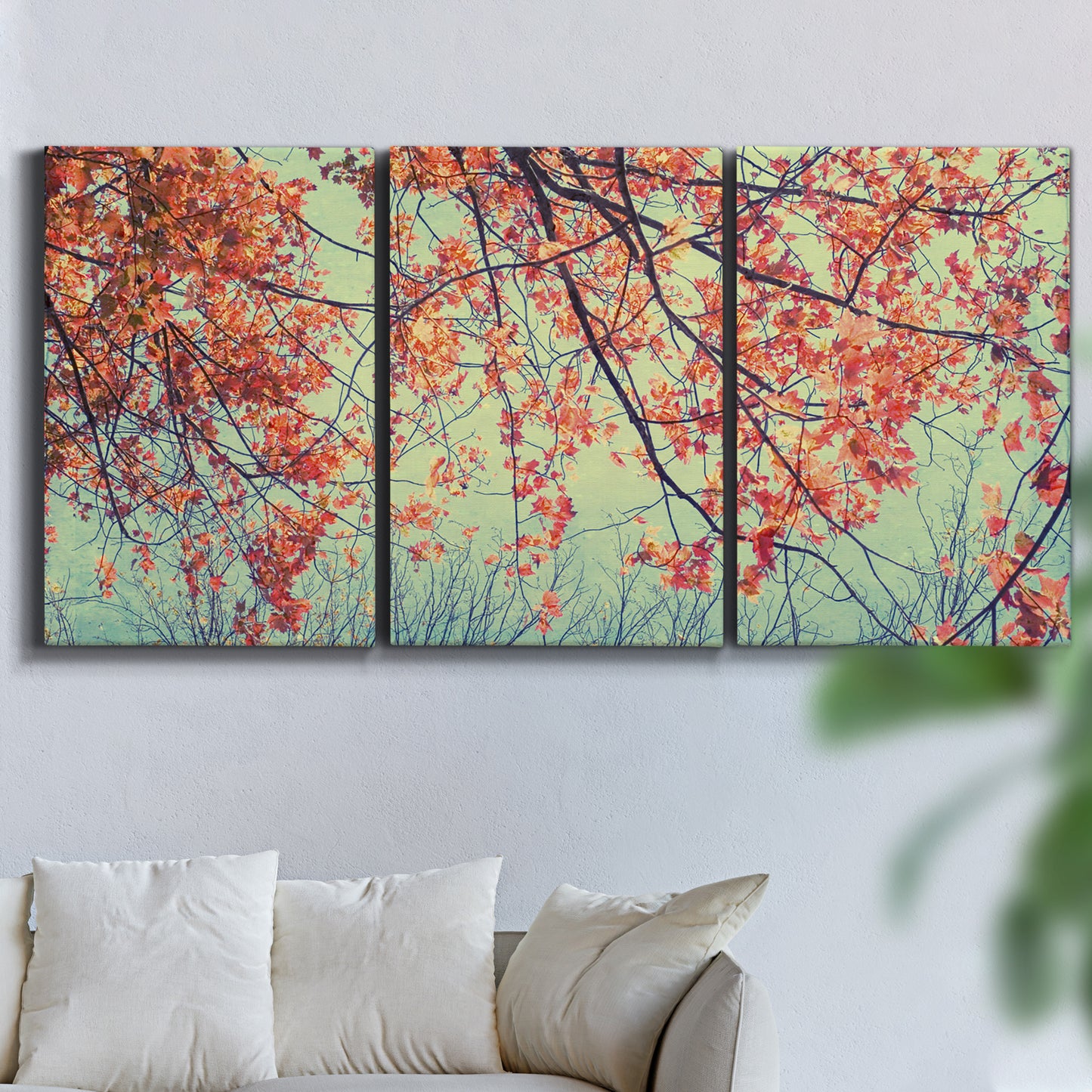 Three-panel canvas wall art featuring autumn foliage landscape photograph, displayed in a living room above a sofa.