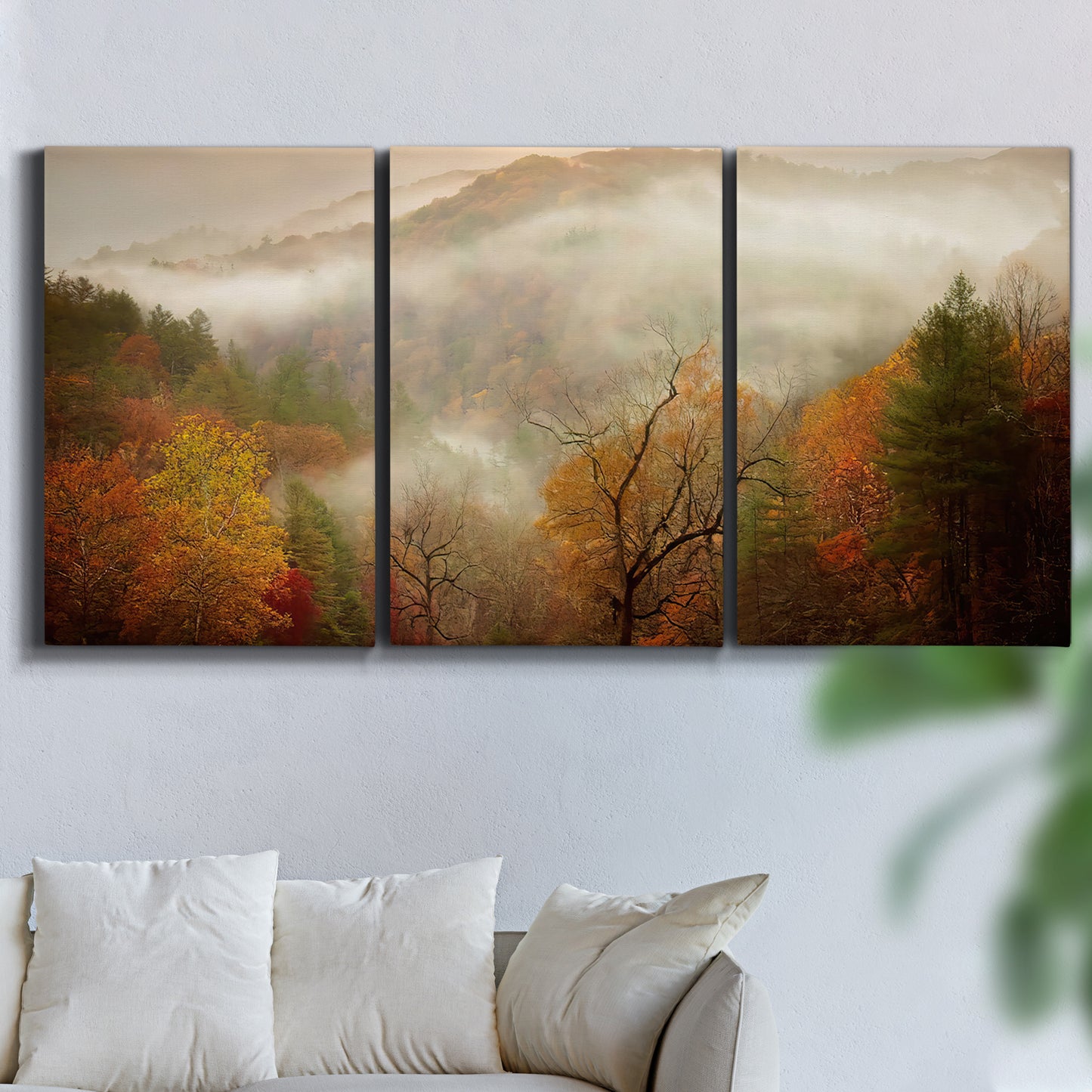 Three-panel canvas wall art featuring misty autumn landscape photograph, displayed in a living room above a sofa.