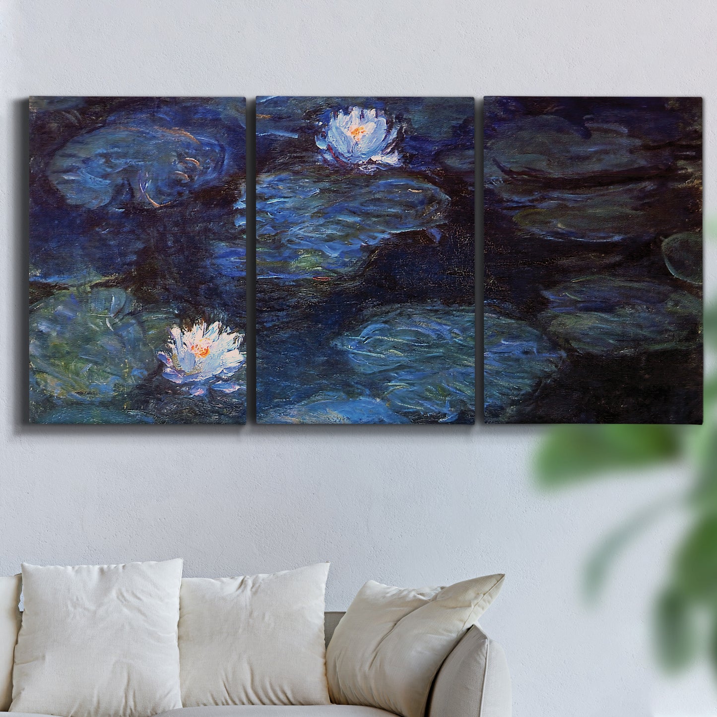 Three-panel canvas wall art featuring deep blue water lily reflections, displayed in a living room above a sofa.