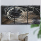 Three-panel canvas wall art featuring dark swirling abstract motion, displayed in a living room above a sofa.