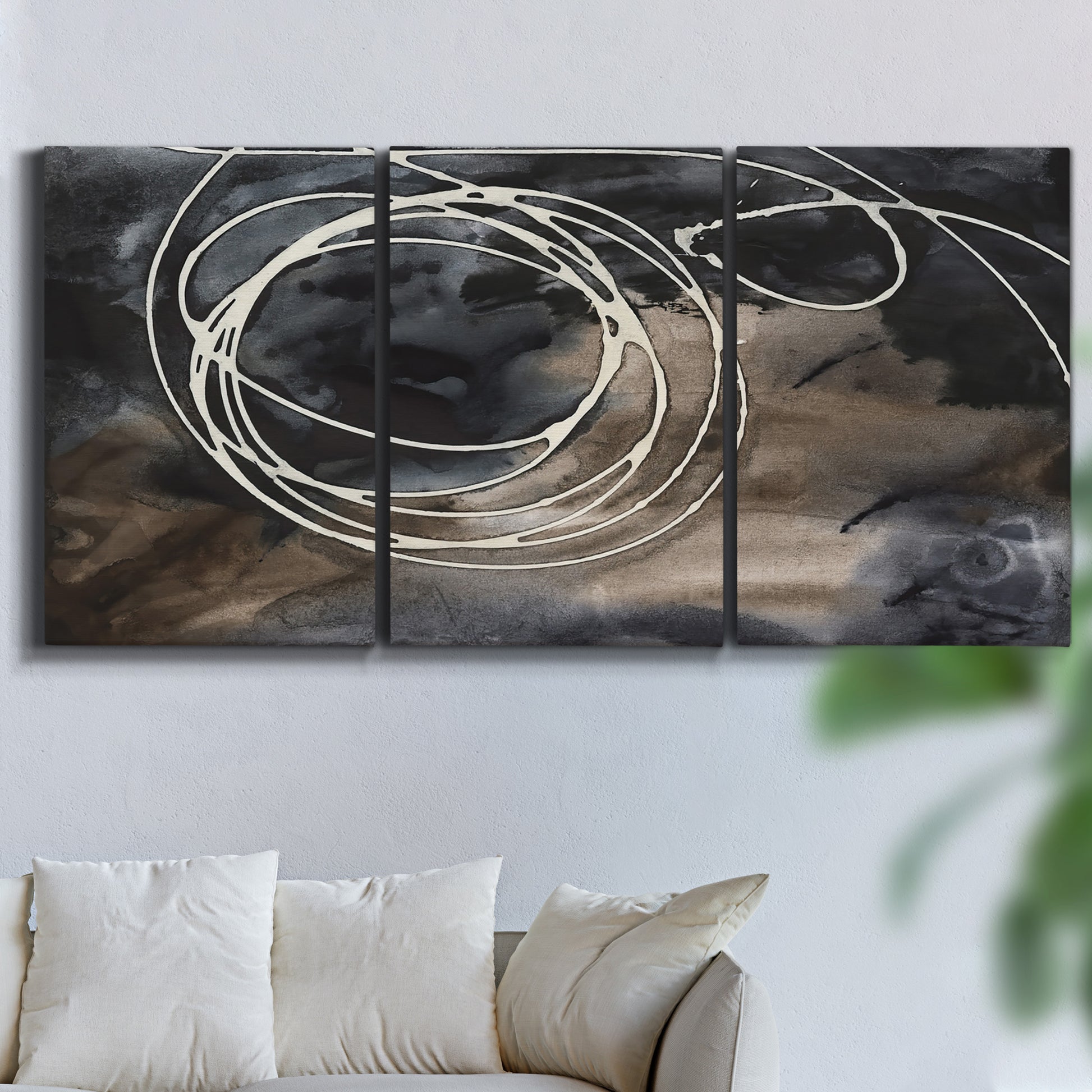 Three-panel canvas wall art featuring dark swirling abstract motion, displayed in a living room above a sofa.