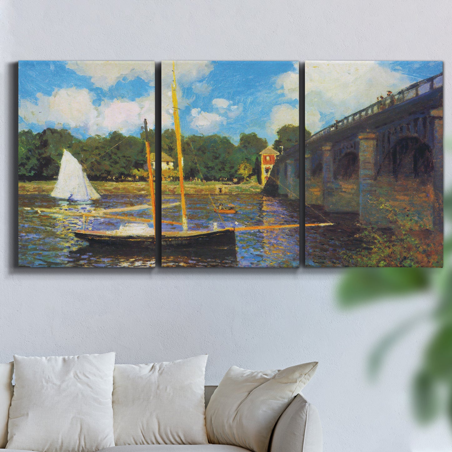 Three-panel canvas wall art featuring bridge crossing river landscape, displayed in a living room above a sofa.