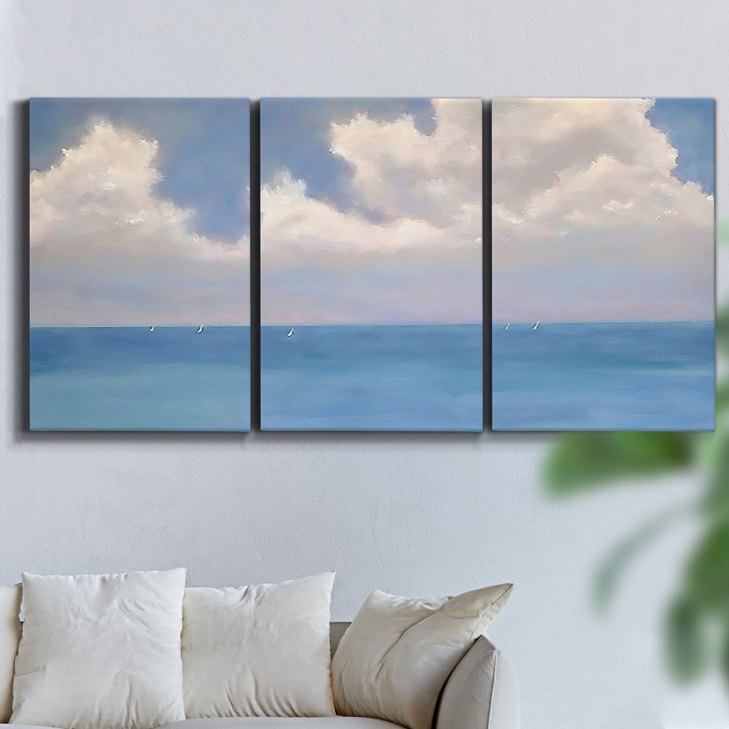 Three-panel canvas wall art featuring coastal shoreline with distant horizon, displayed in a living room above a sofa.