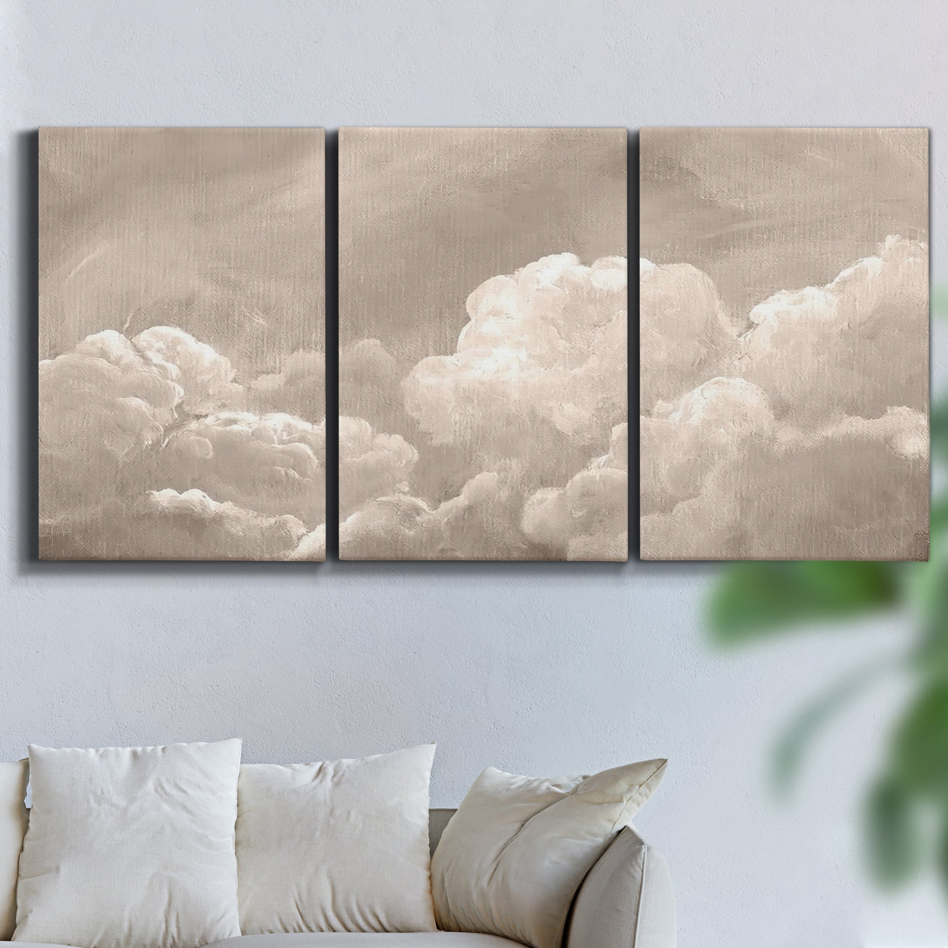 Three-panel canvas wall art featuring soft whimsical cloudscape, displayed in a living room above a sofa.