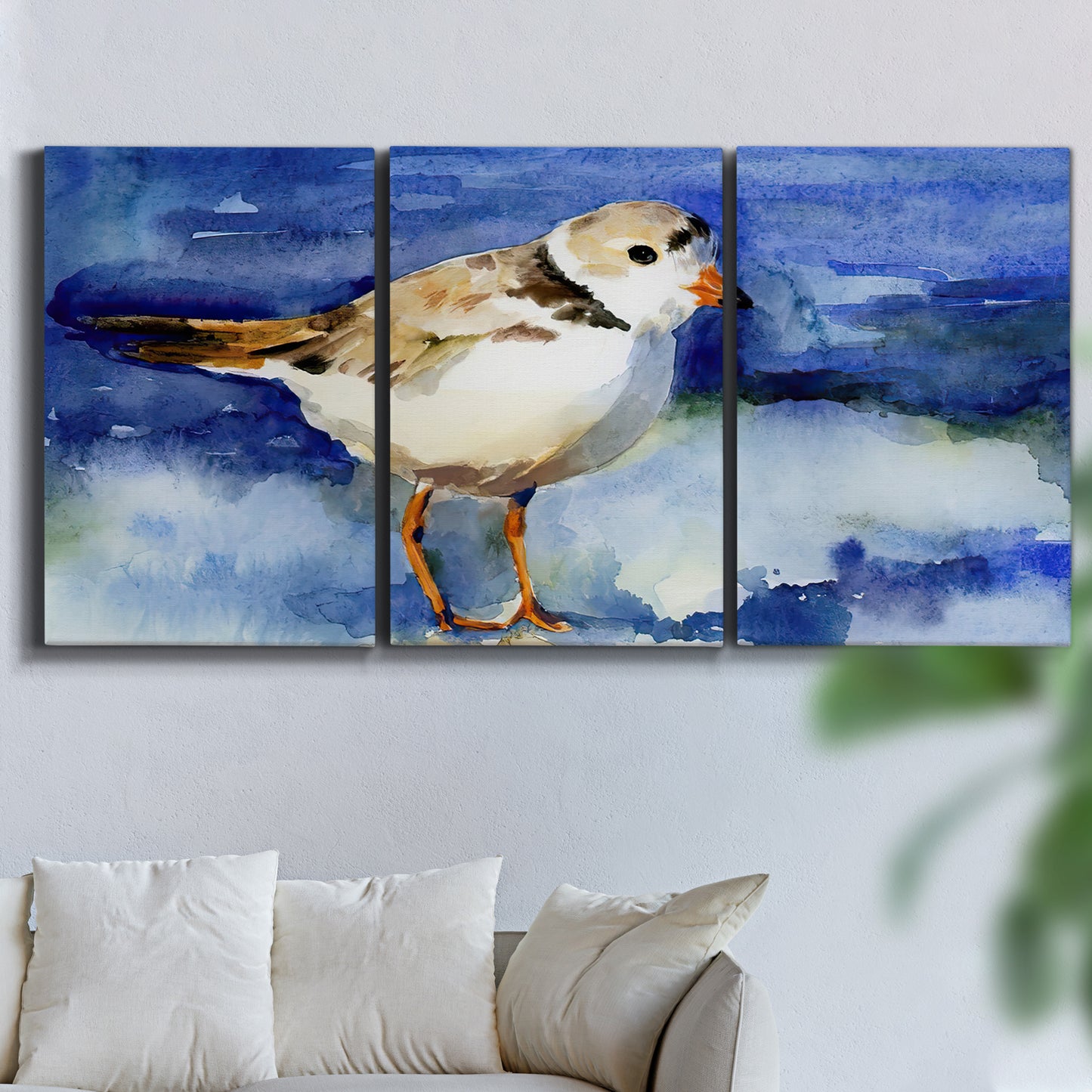 Three-panel canvas wall art featuring shorebirds standing in shallow water, displayed in a living room above a sofa.