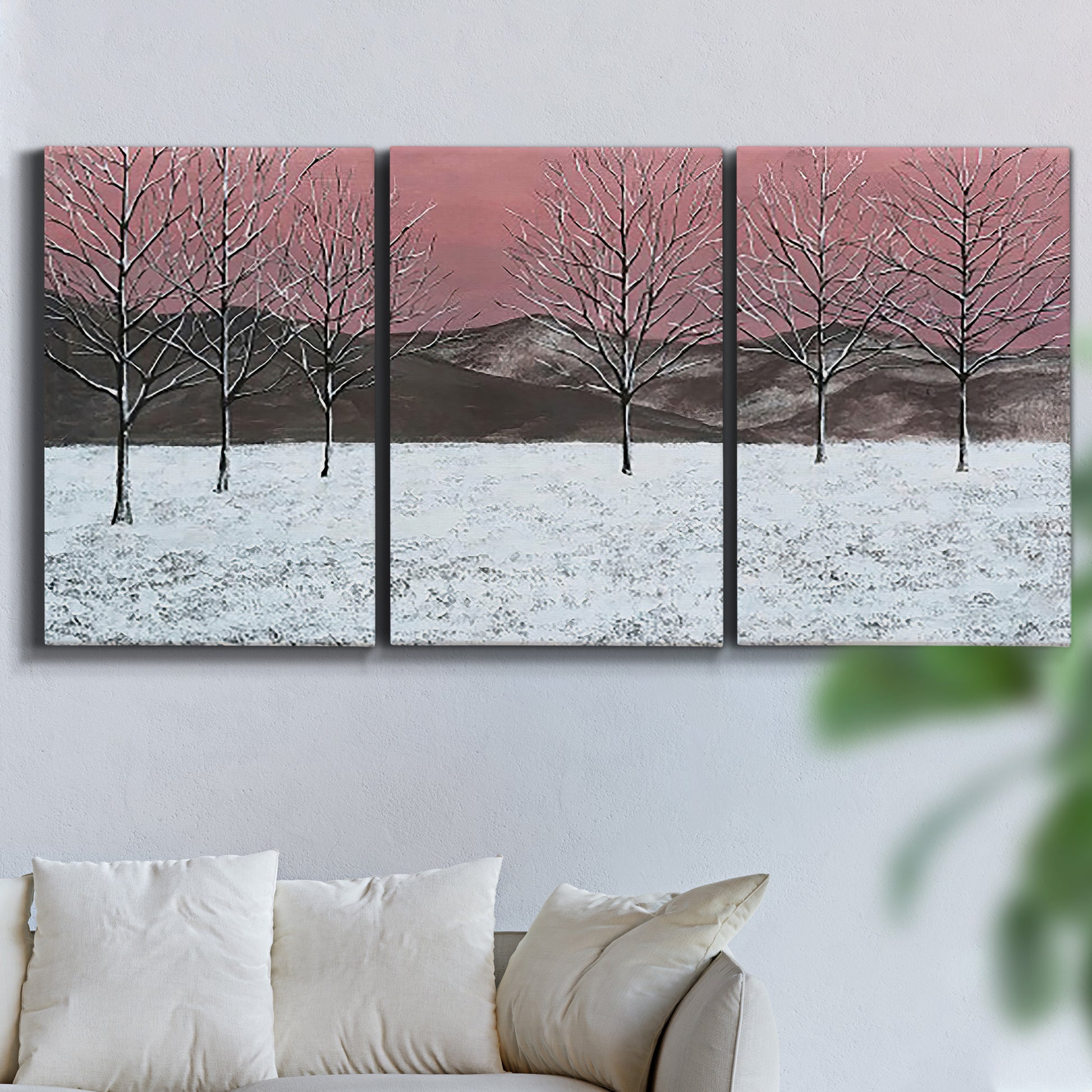 Three-panel canvas wall art featuring winter sunset snowfall landscape, displayed in a living room above a sofa.