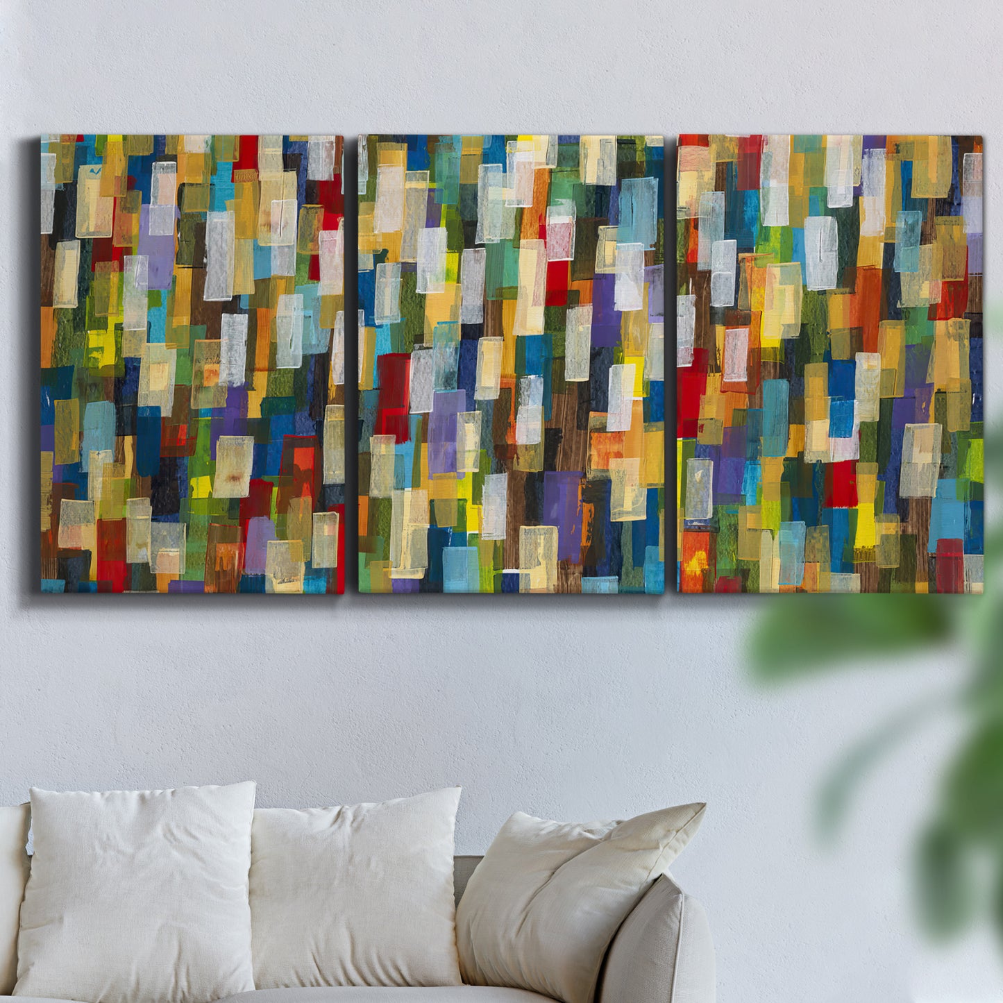 Three-panel canvas wall art featuring colorful confetti style abstraction, displayed in a living room above a sofa.
