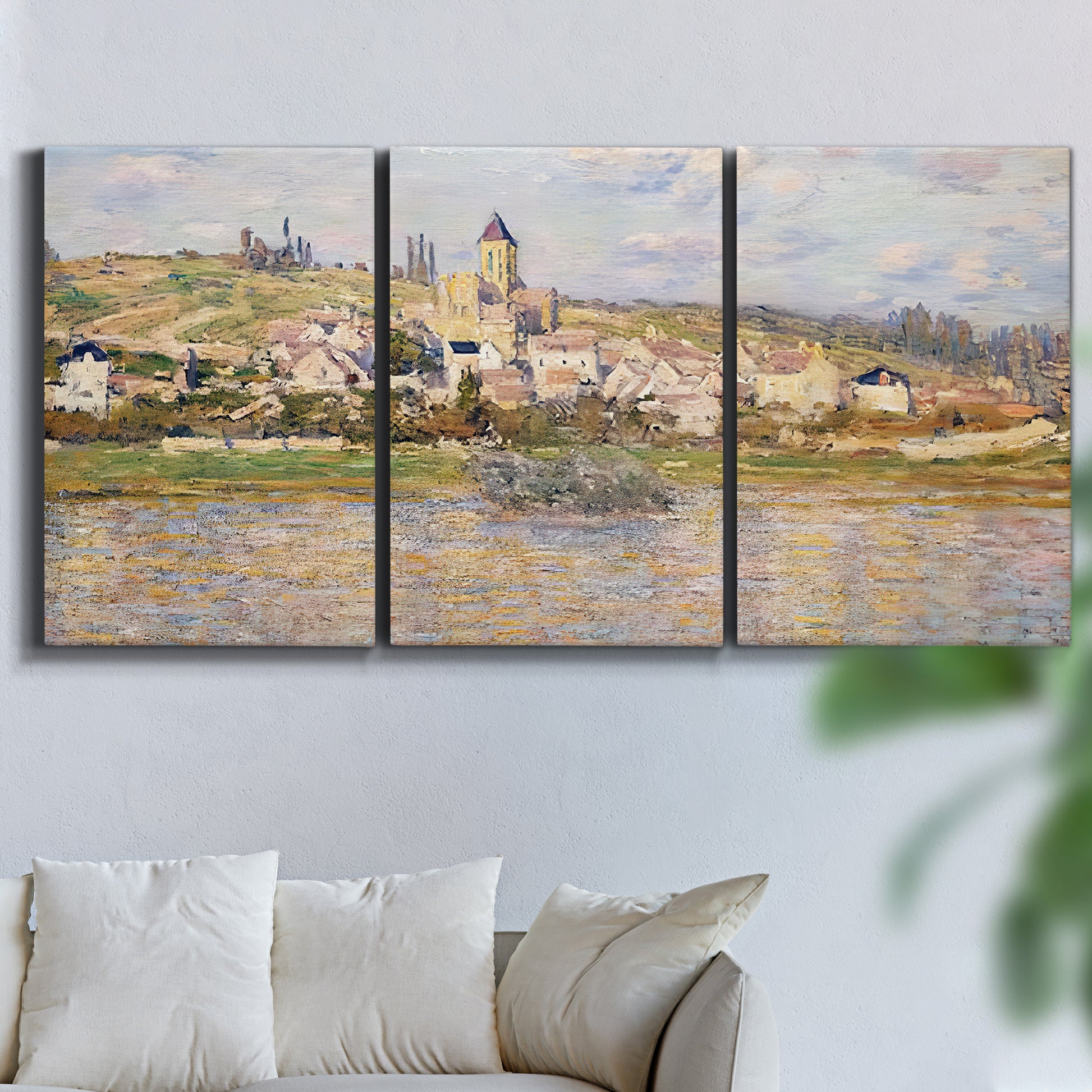 Three-panel canvas wall art featuring village overlooking river valley, displayed in a living room above a sofa.