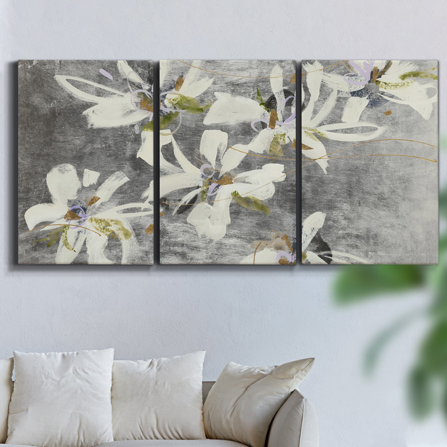 Three-panel canvas wall art featuring delicate floral symbolic arrangement, displayed in a living room above a sofa.