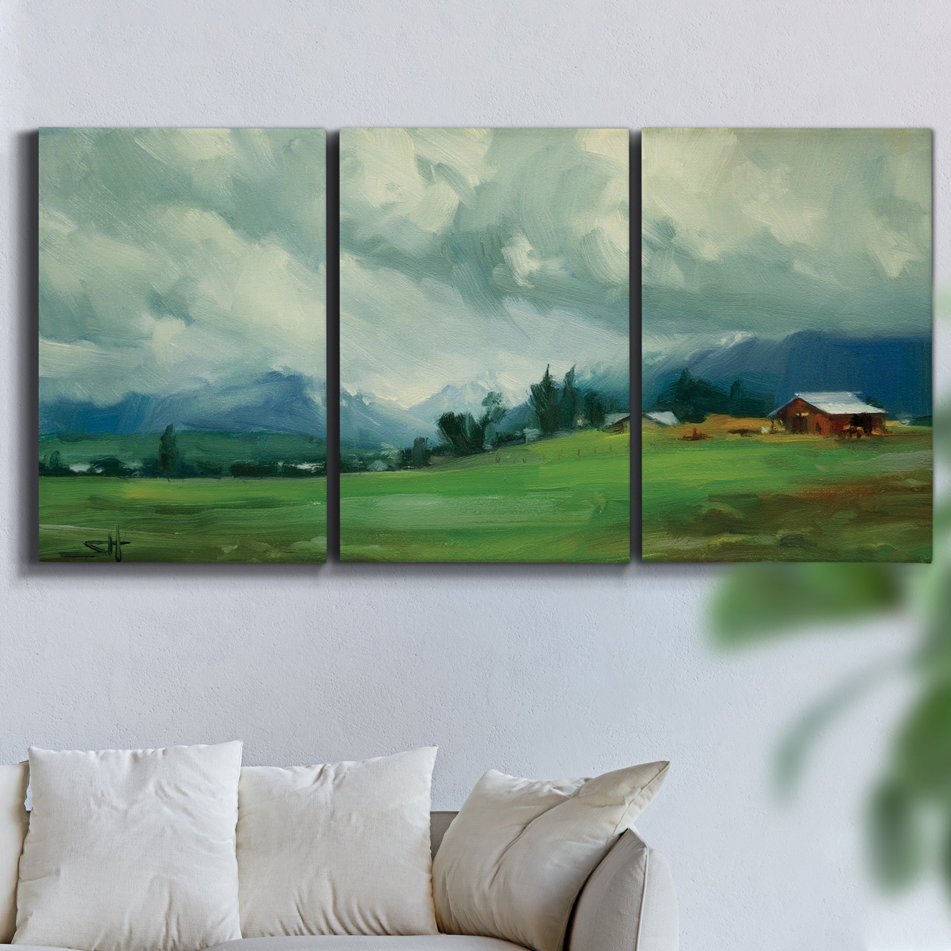 Three-panel canvas wall art featuring wide pastoral valley landscape, displayed in a living room above a sofa.