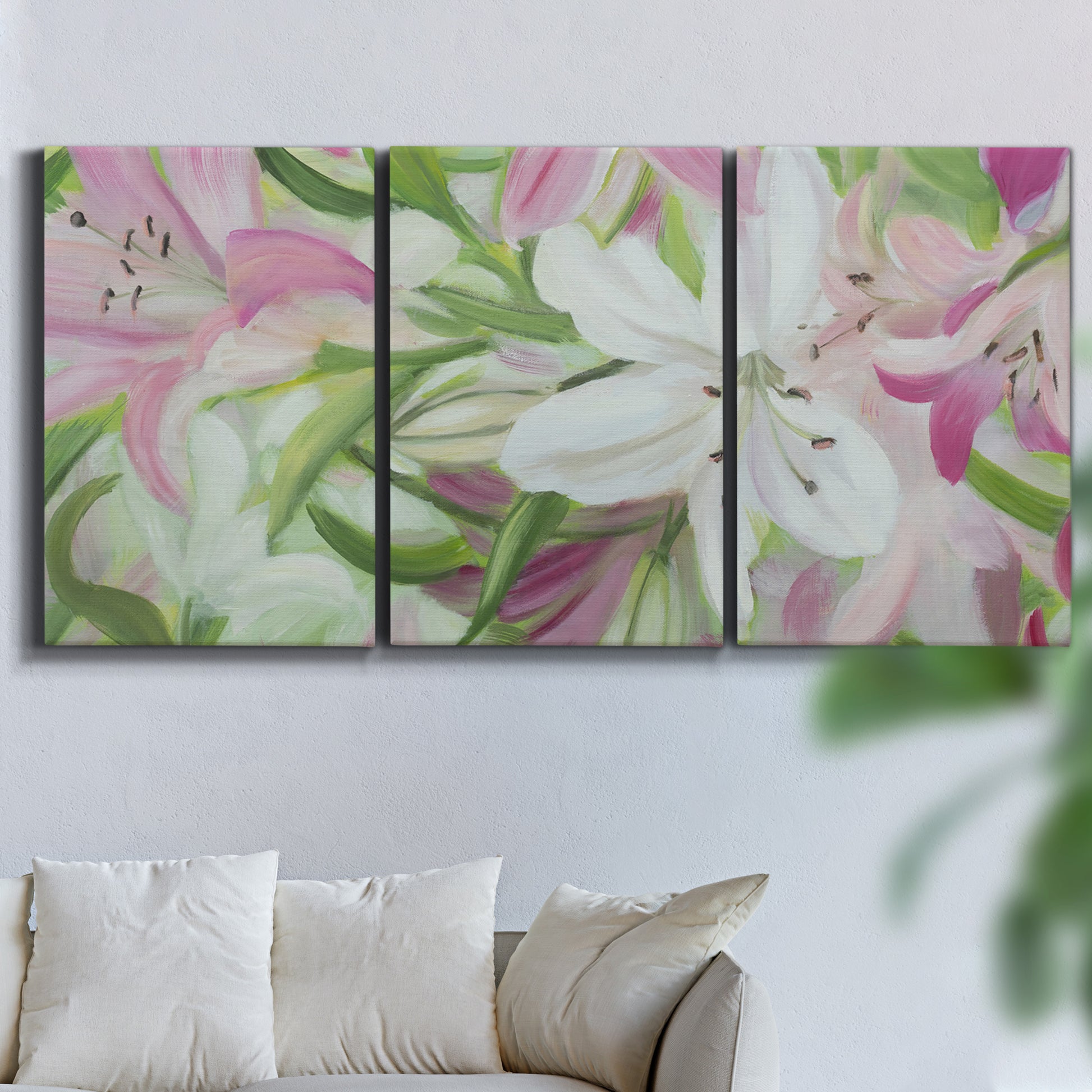 Three-panel canvas wall art featuring pink and white lilies botanical study, displayed in a living room above a sofa.