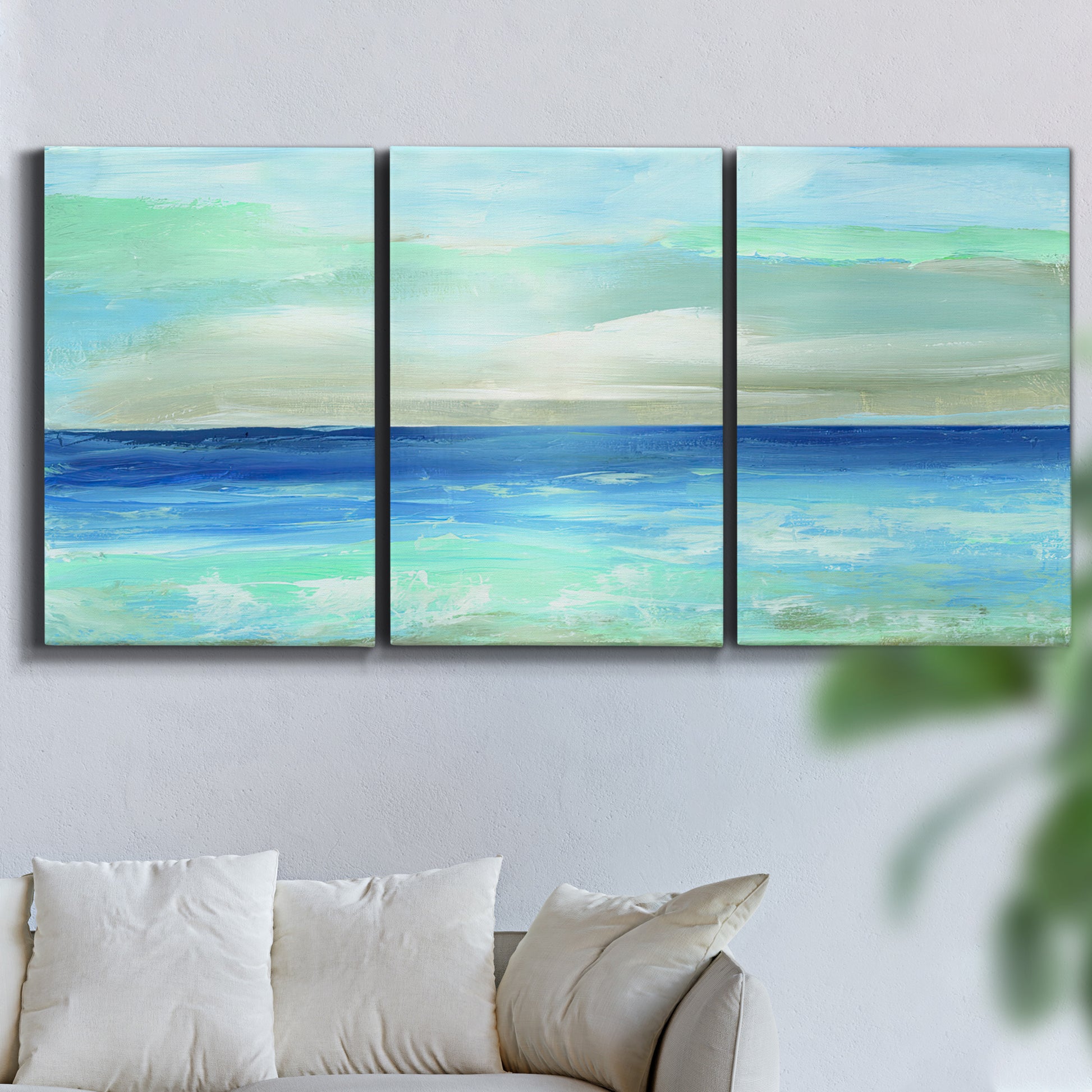 Three-panel canvas wall art featuring vast open blue ocean horizon, displayed in a living room above a sofa.