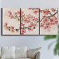 Three-panel canvas wall art featuring blooming cherry blossom branches, displayed in a living room above a sofa.