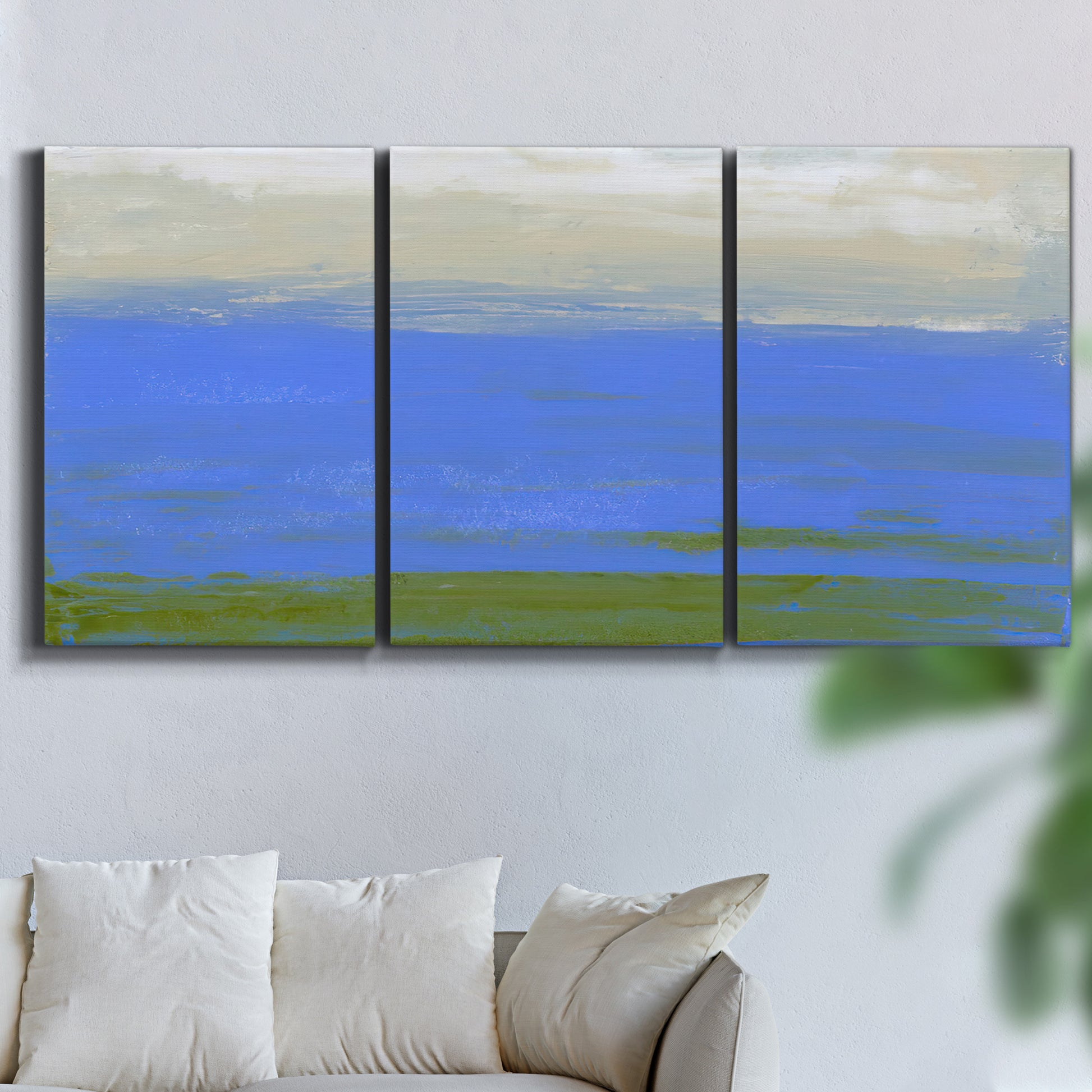 Three-panel canvas wall art featuring abstract coastal inlet landscape, displayed in a living room above a sofa.