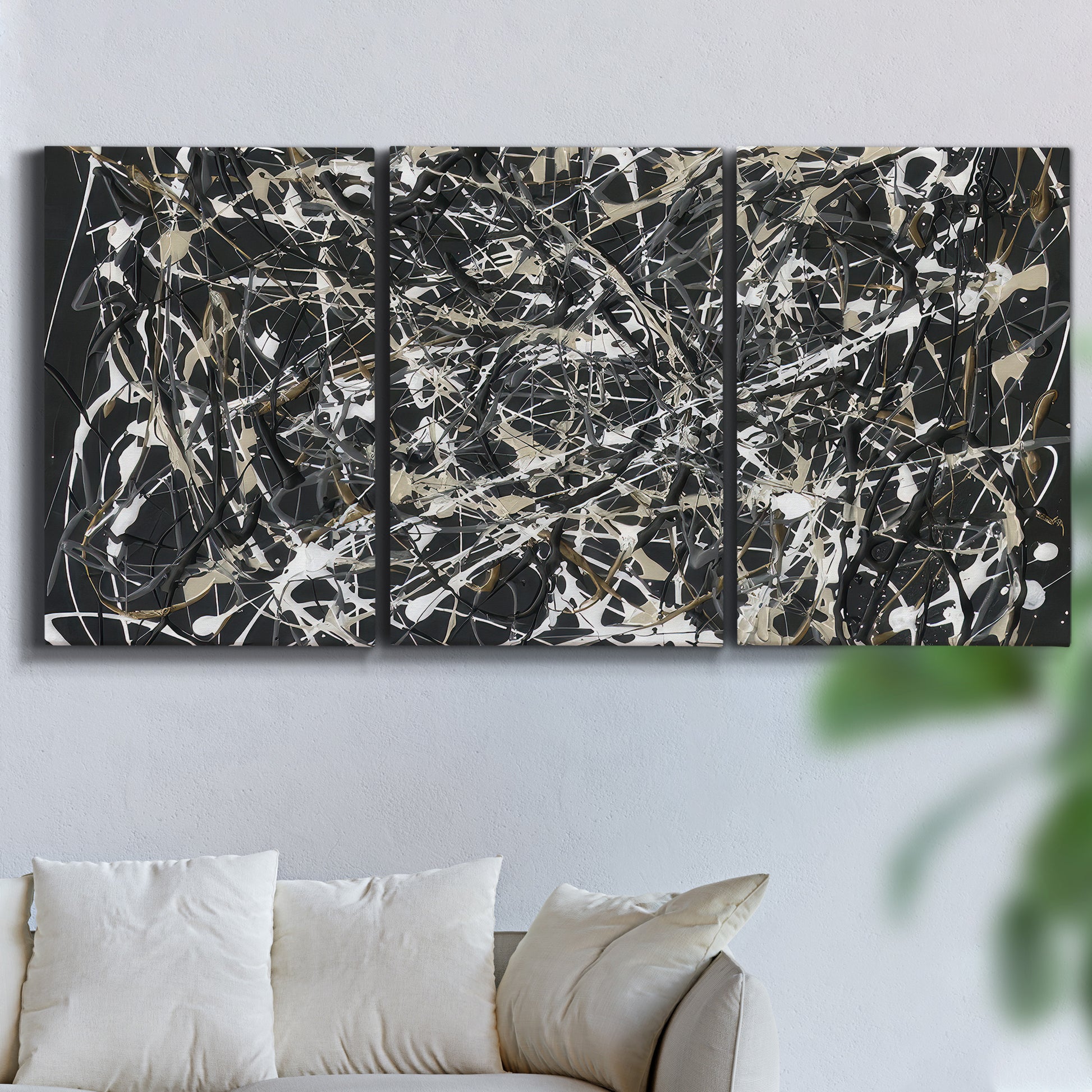 Three-panel canvas wall art featuring energetic expressionist abstract splatter, displayed in a living room above a sofa.