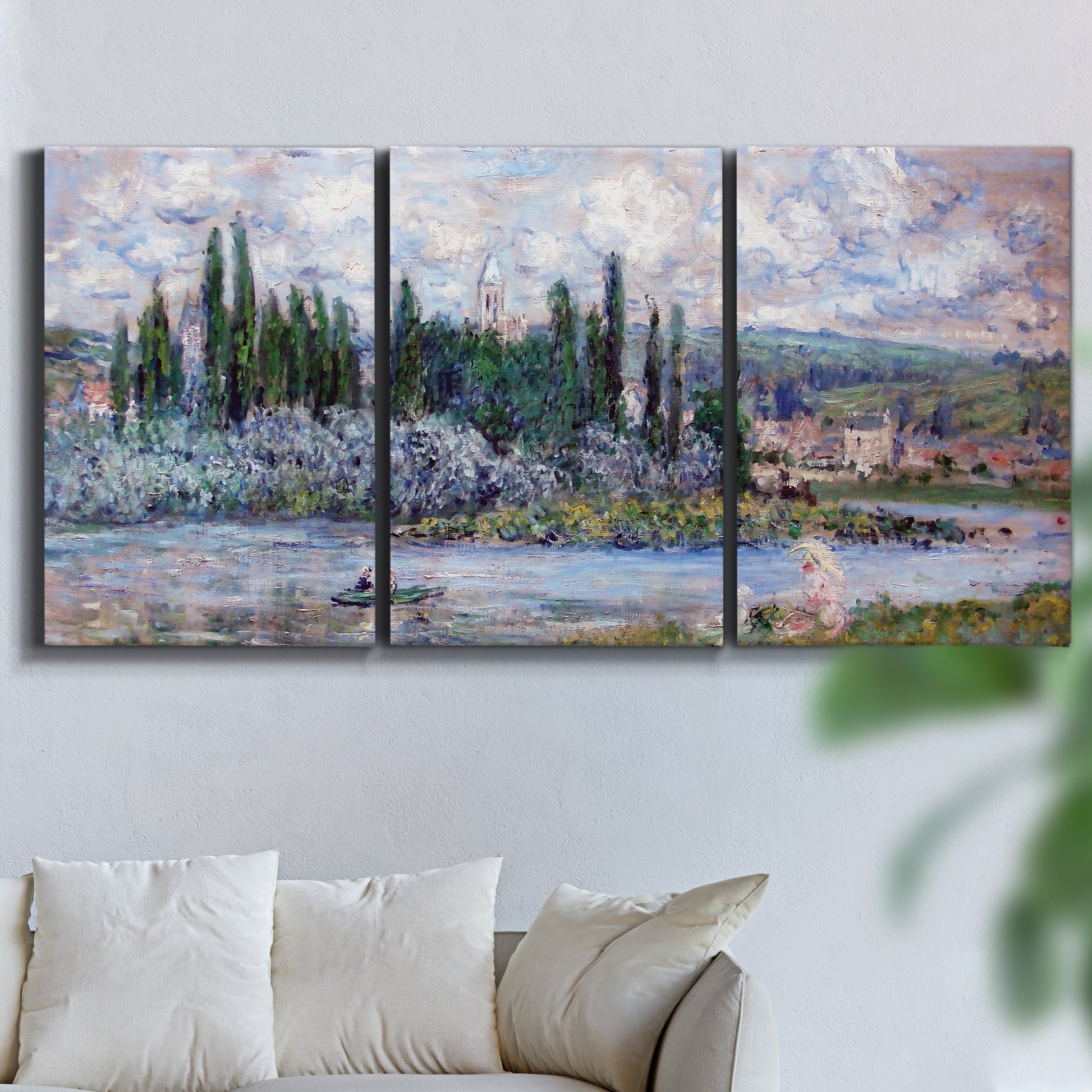 Three-panel canvas wall art featuring summer village view along river, displayed in a living room above a sofa.