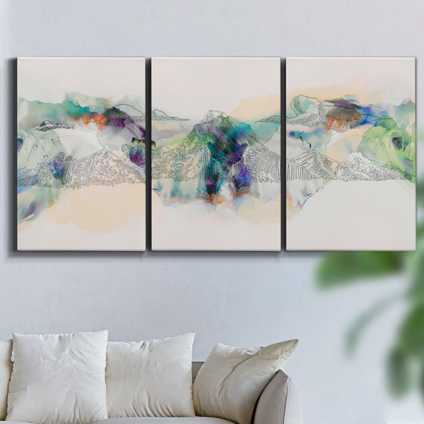 Three-panel canvas wall art featuring abstract mountain range watercolor, displayed in a living room above a sofa.
