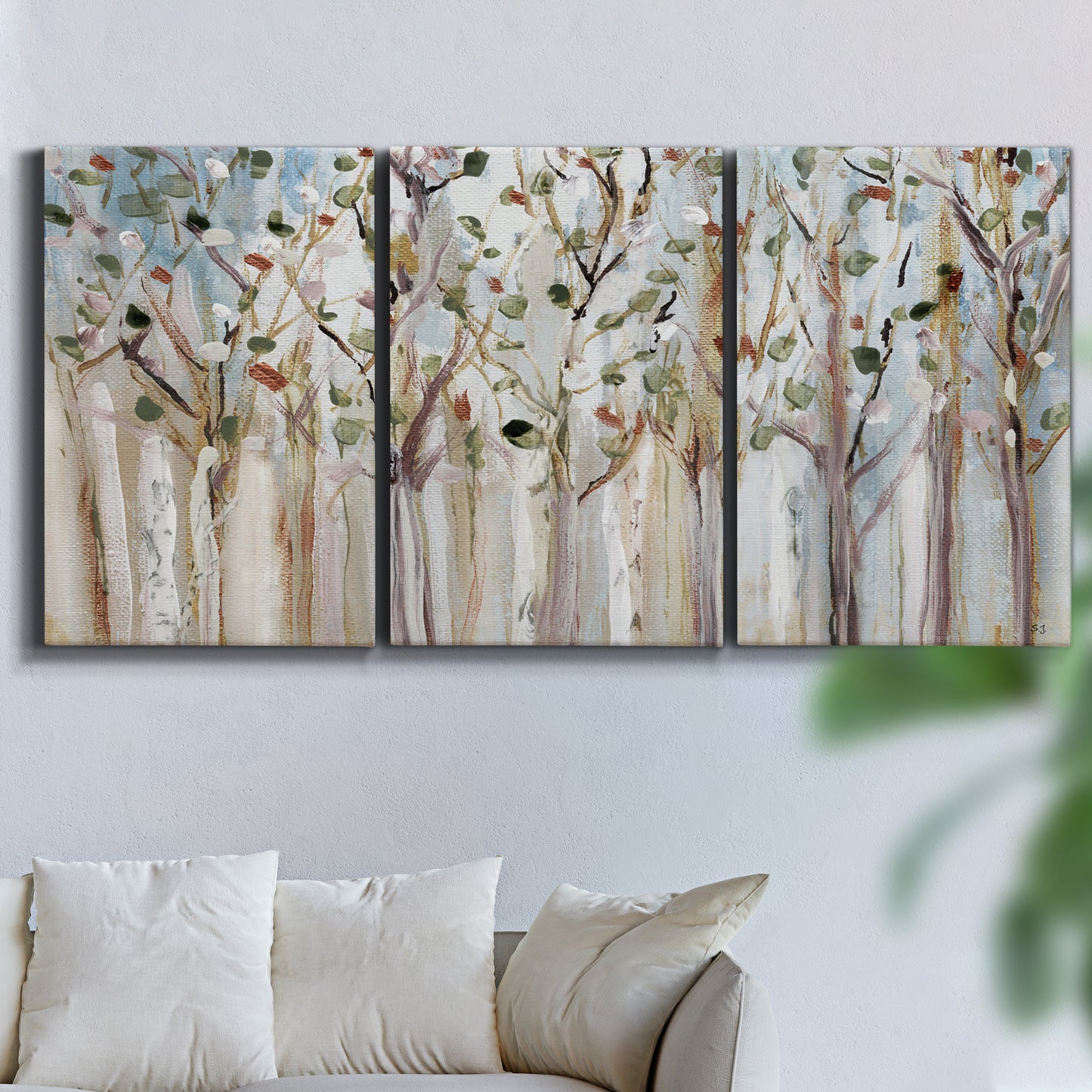 Three-panel canvas wall art featuring bare birch trees in winter forest, displayed in a living room above a sofa.