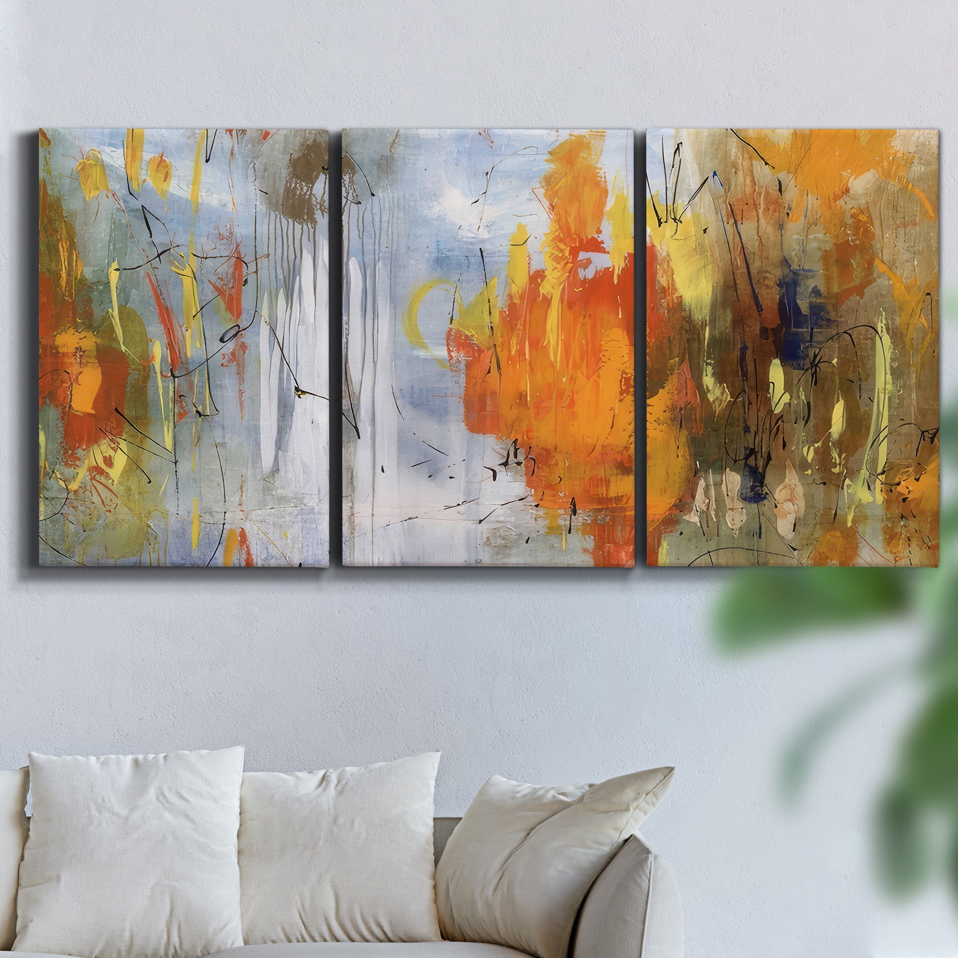 Three-panel canvas wall art featuring abstract warm sunset tones, displayed in a living room above a sofa.