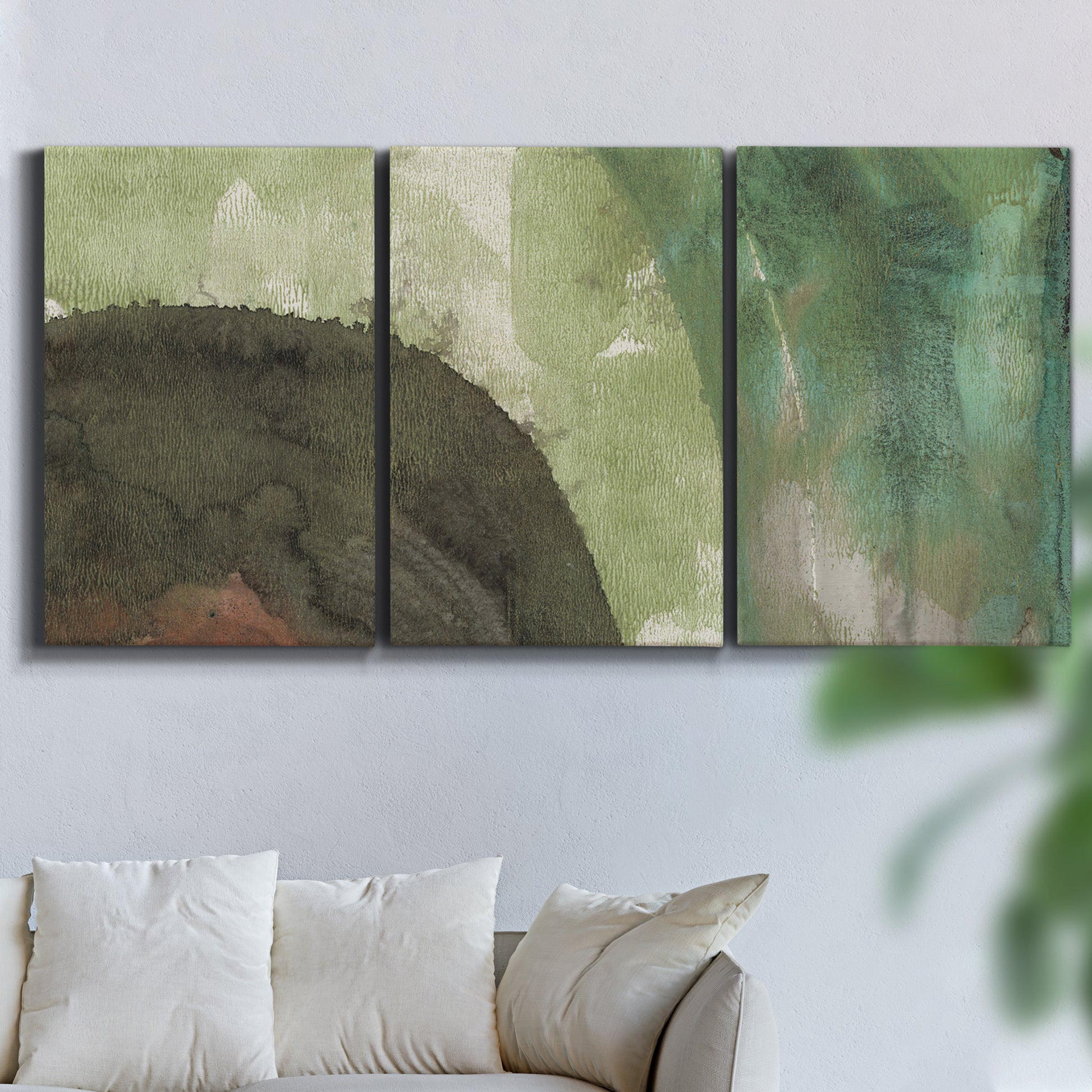 Three-panel canvas wall art featuring layered green abstract composition, displayed in a living room above a sofa.