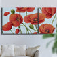 Three-panel canvas wall art featuring red poppies in motion, displayed in a living room above a sofa.